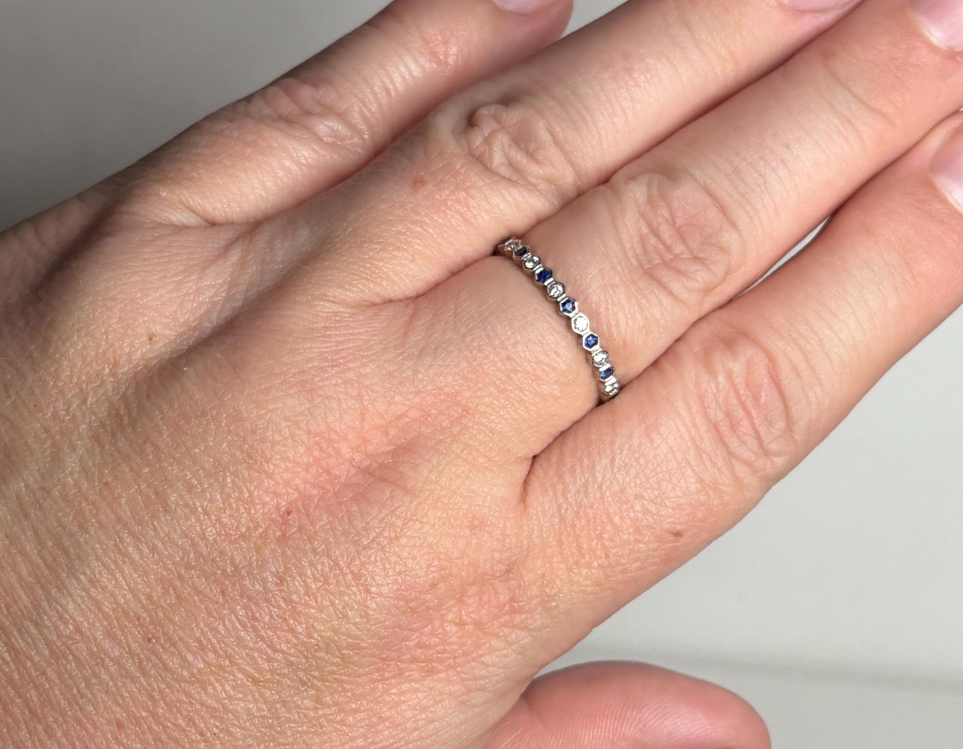 A 14k white gold band ring with alternating blue sapphires and diamonds in a honeycomb hexagon pattern.