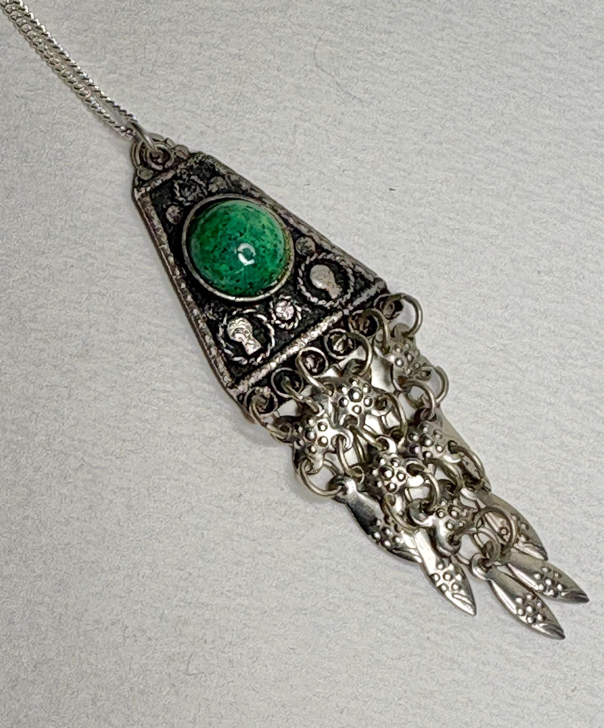 Sterling silver pendant with green stone and fringe detail.