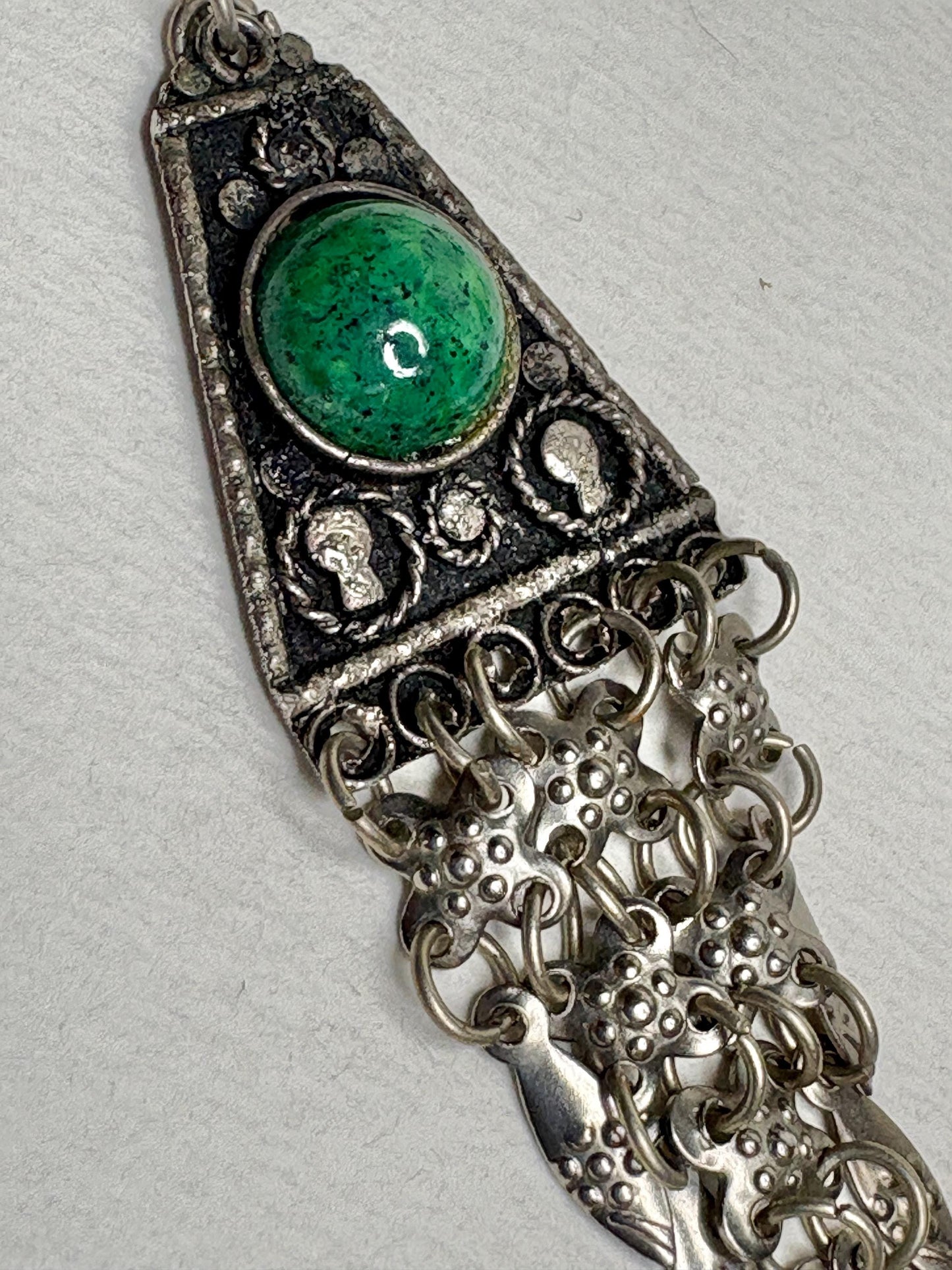 Sterling silver pendant with green stone and dangling chains.