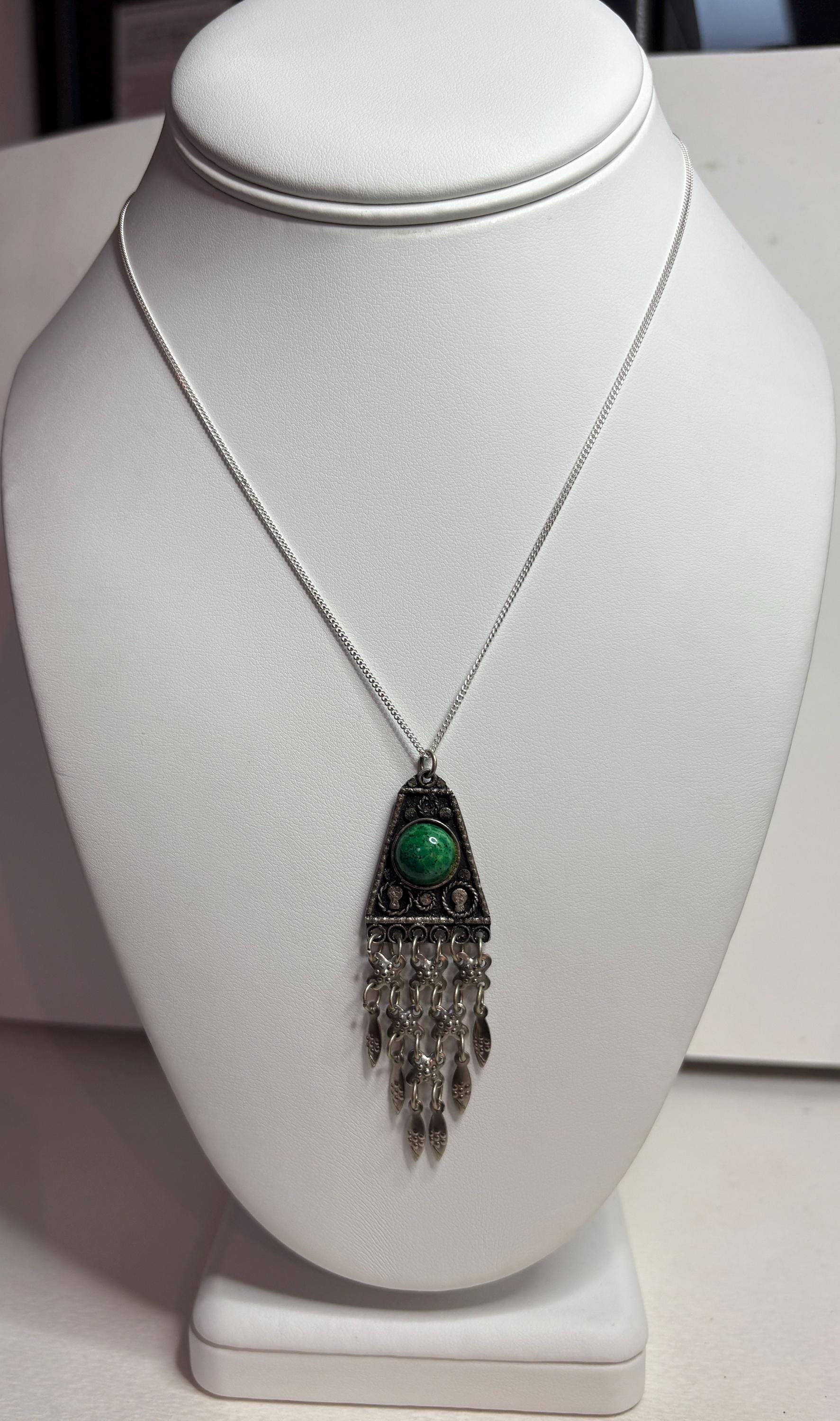 Sterling silver pendant with green stone and fringe detail.