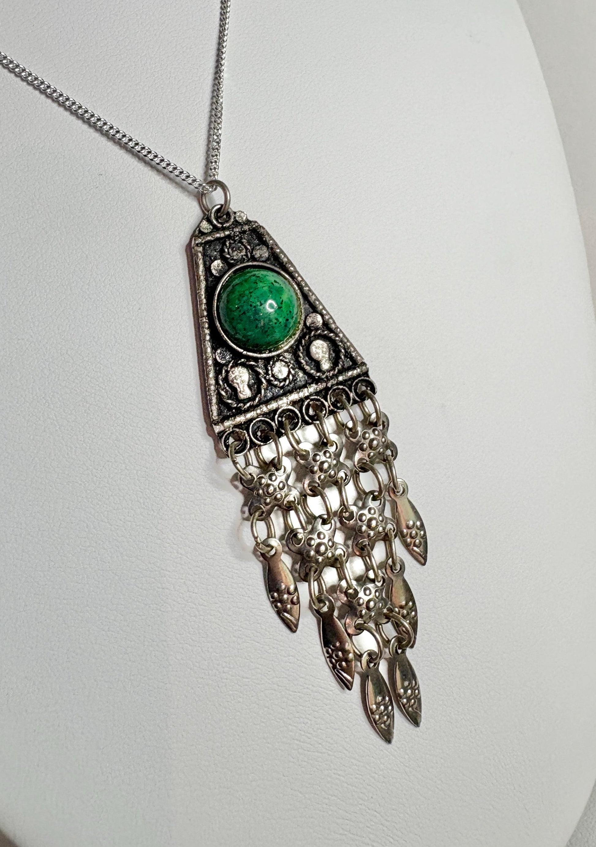 Sterling silver pendant with green stone and dangling fringe.