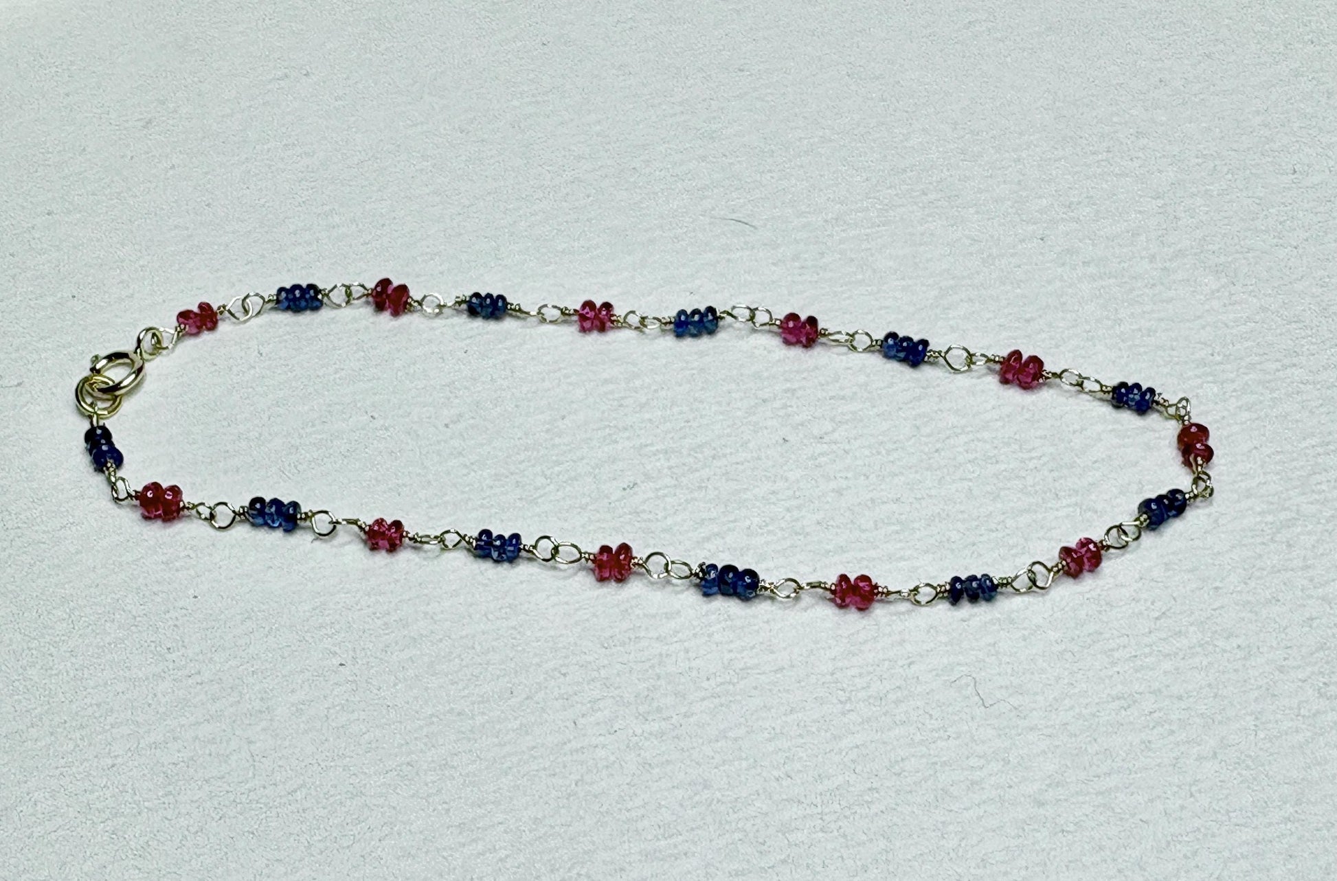 A dainty 14k gold bracelet with smooth Burmese sapphire and red spinel beads.