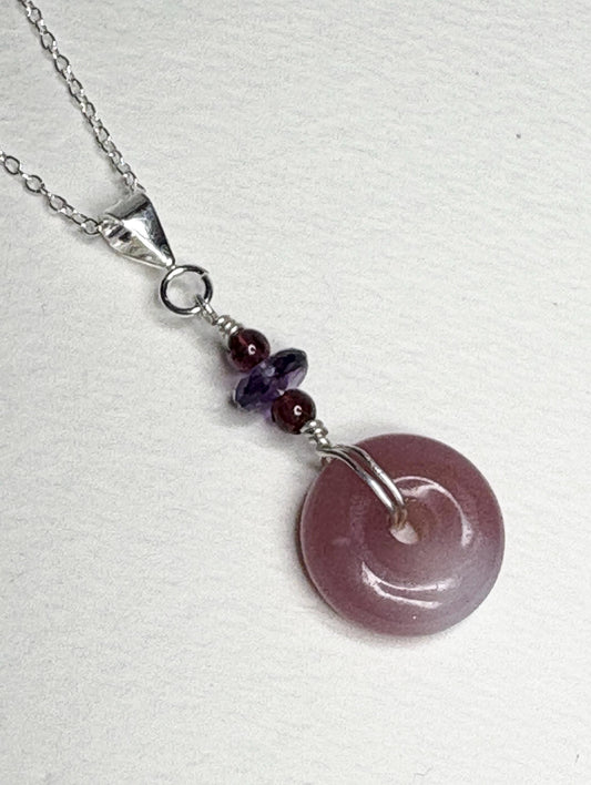 Sterling silver pendant necklace with a mauve-pink agate donut and amethyst and garnet beads.