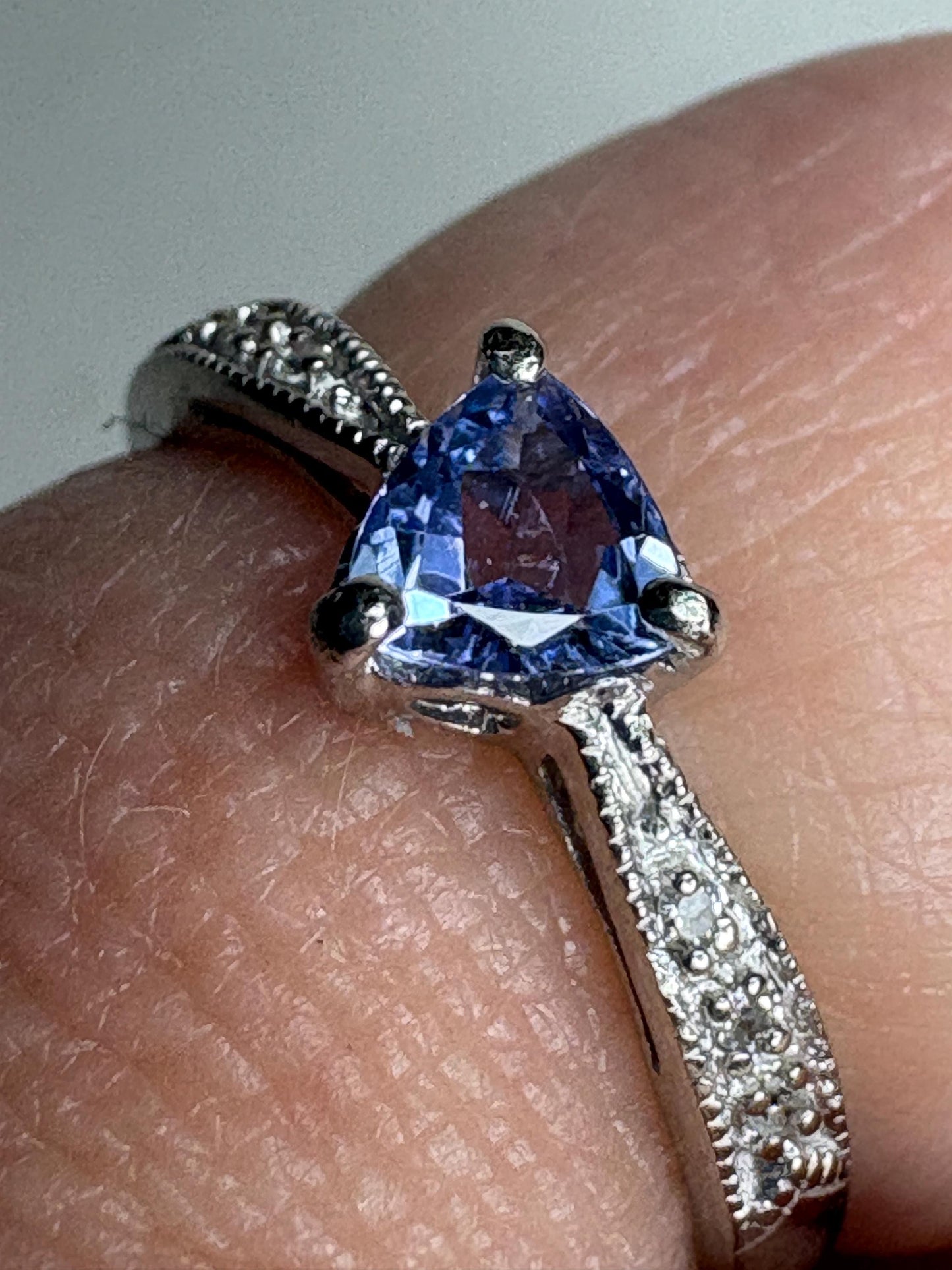 Tanzanite trillion ring with diamonds on a white gold band.