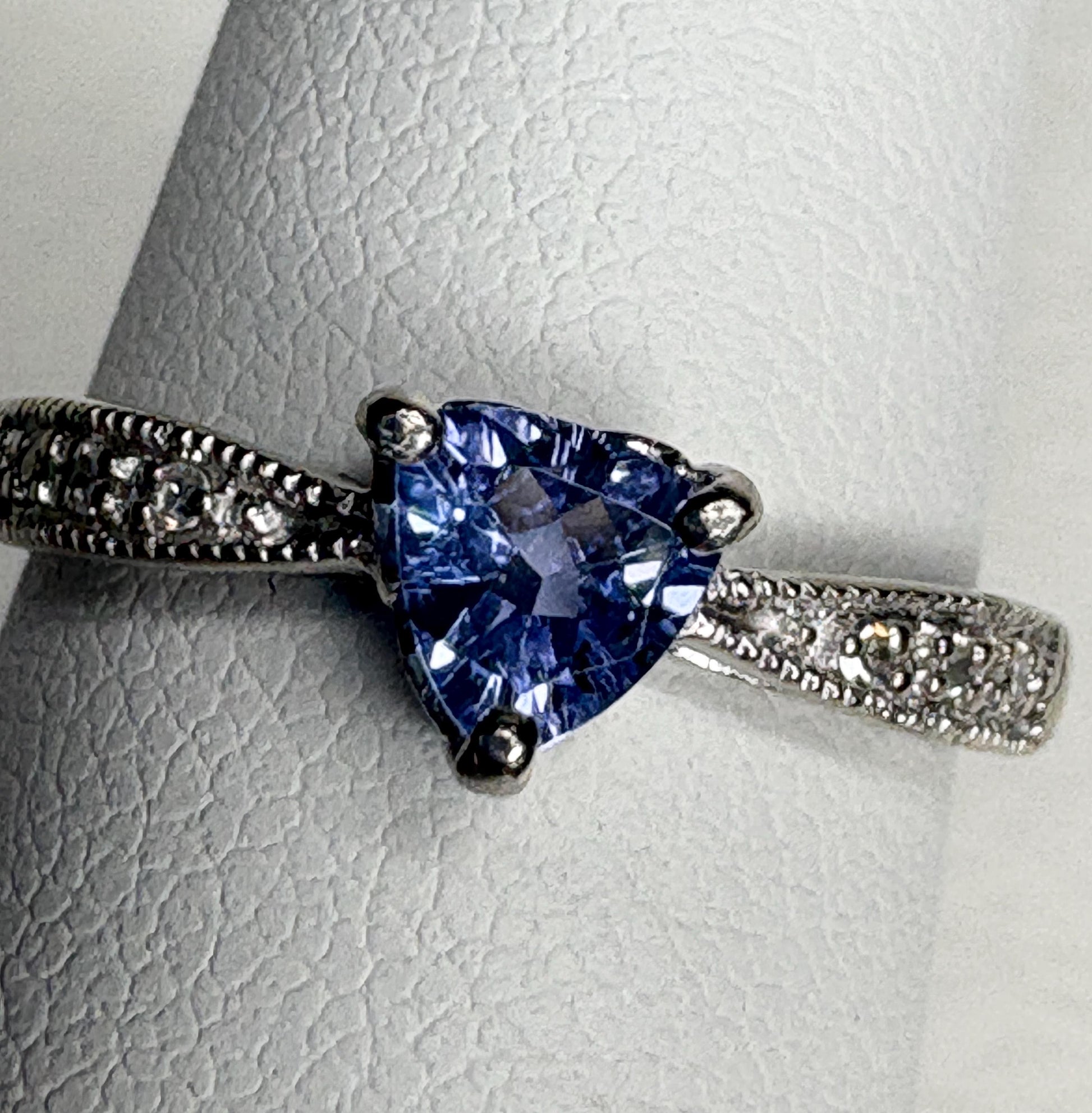 Tanzanite trillion ring with diamonds on a white gold band.