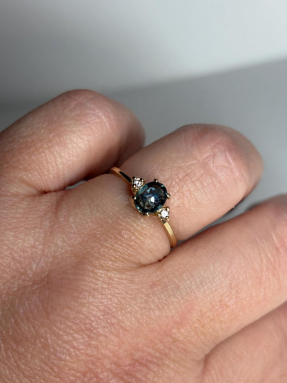 A 14k yellow gold ring with an oval Montana sapphire and two diamonds.