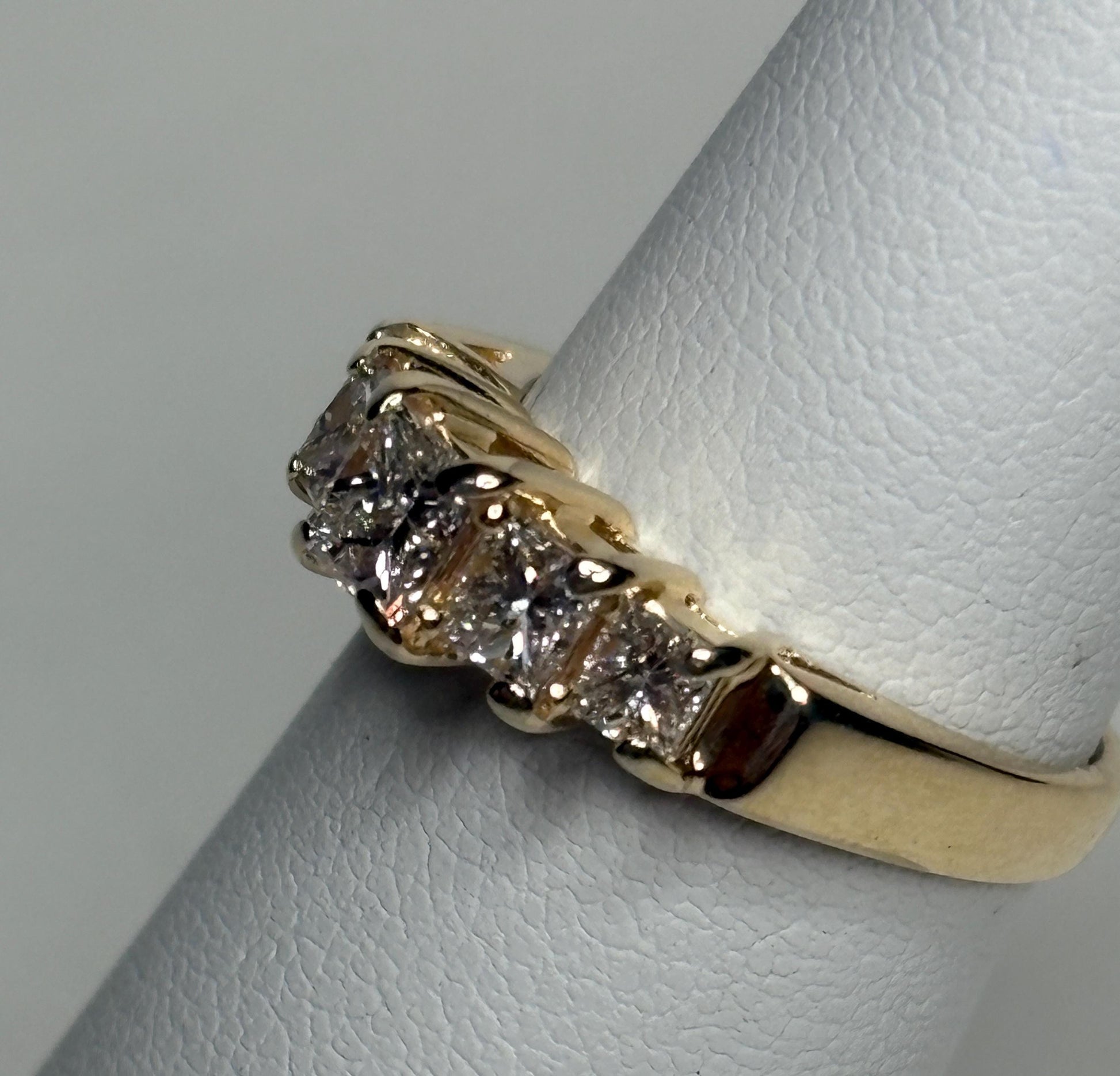 A 14k yellow gold band ring with five princess-cut diamonds.