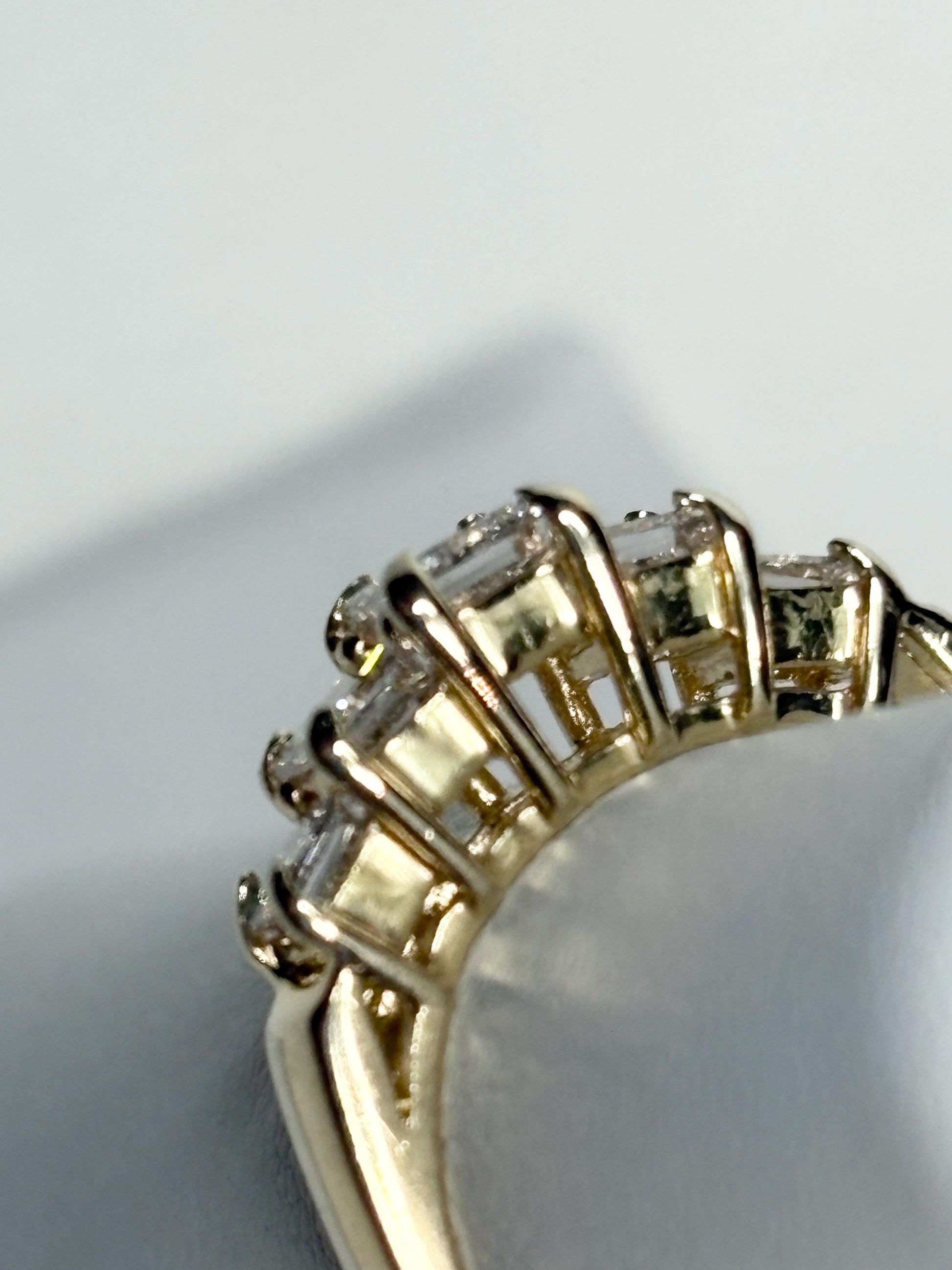 A 14k yellow gold band ring with five princess-cut diamonds.