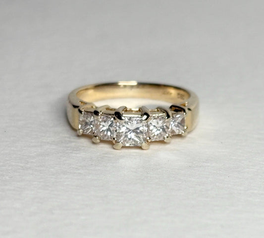 A 14k yellow gold band ring with five princess-cut diamonds.