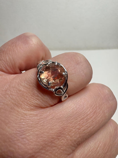 Sterling silver ring with an oval Oregon sunstone in a free-form ribbon setting.