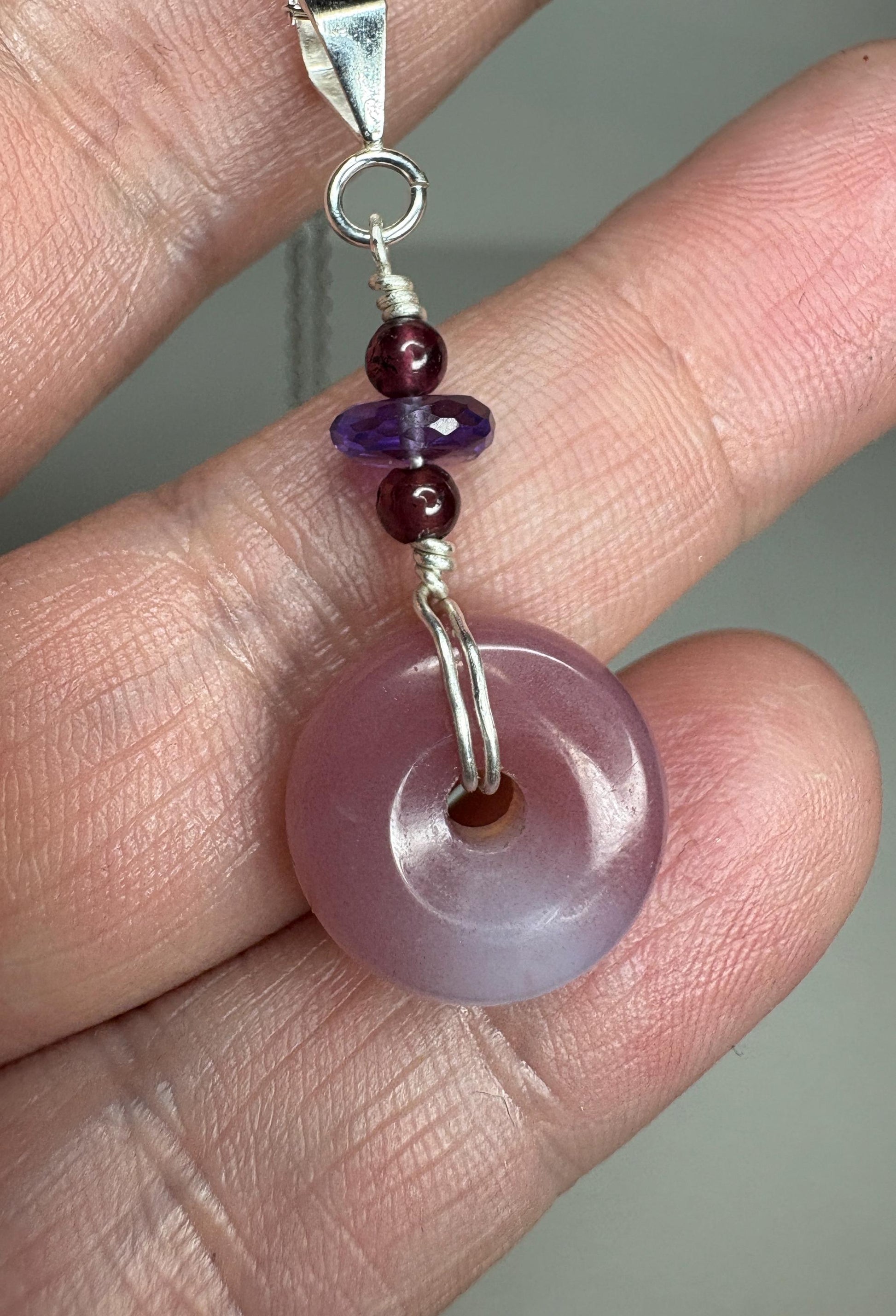Sterling silver pendant necklace with a mauve-pink agate donut, amethyst, and garnet beads.