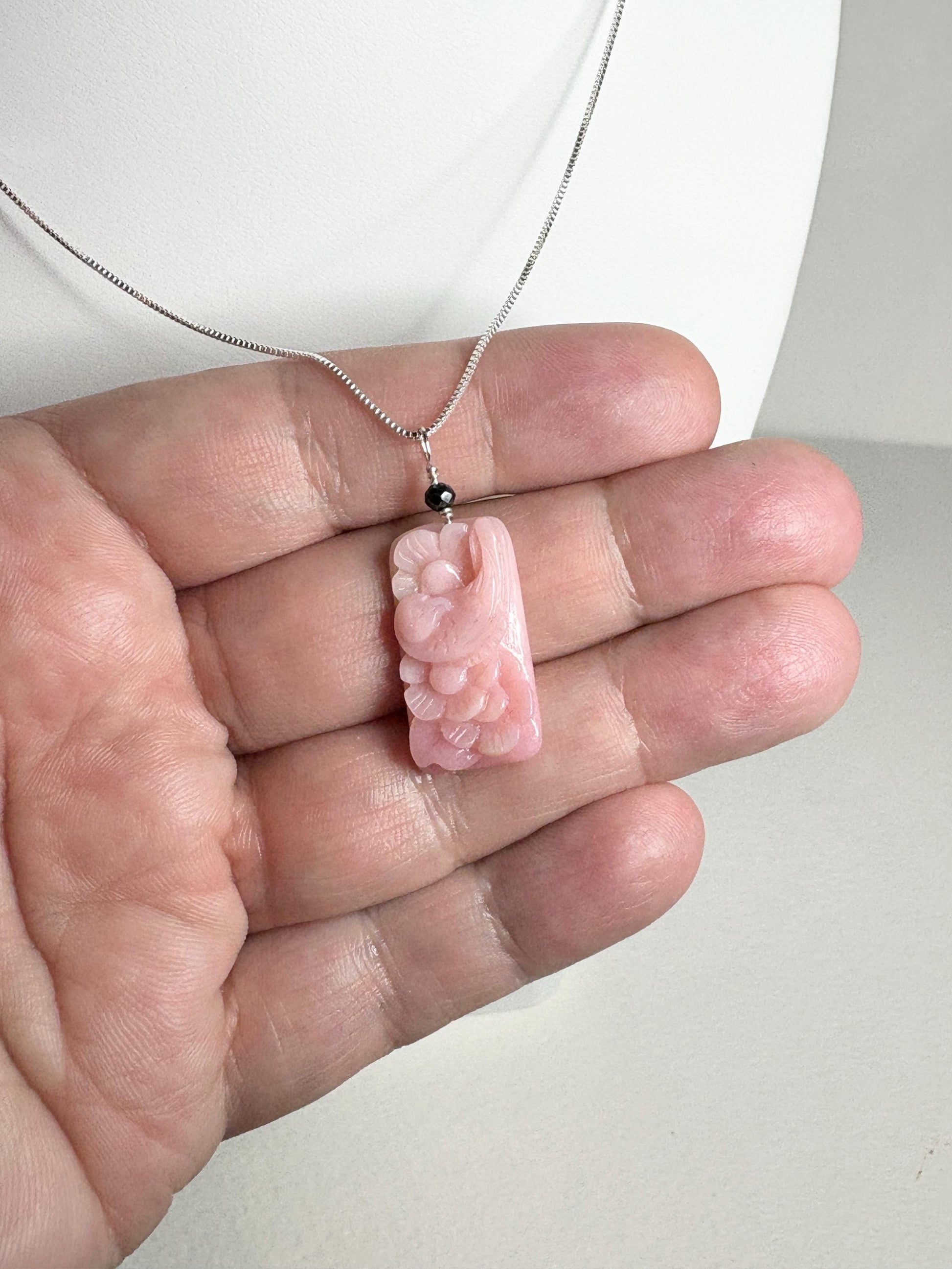 Carved pink opal dove pendant with black diamond on sterling silver chain.