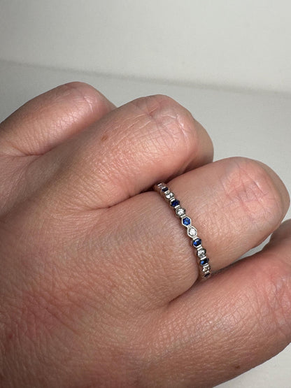A 14k white gold band ring with alternating sapphires and diamonds.