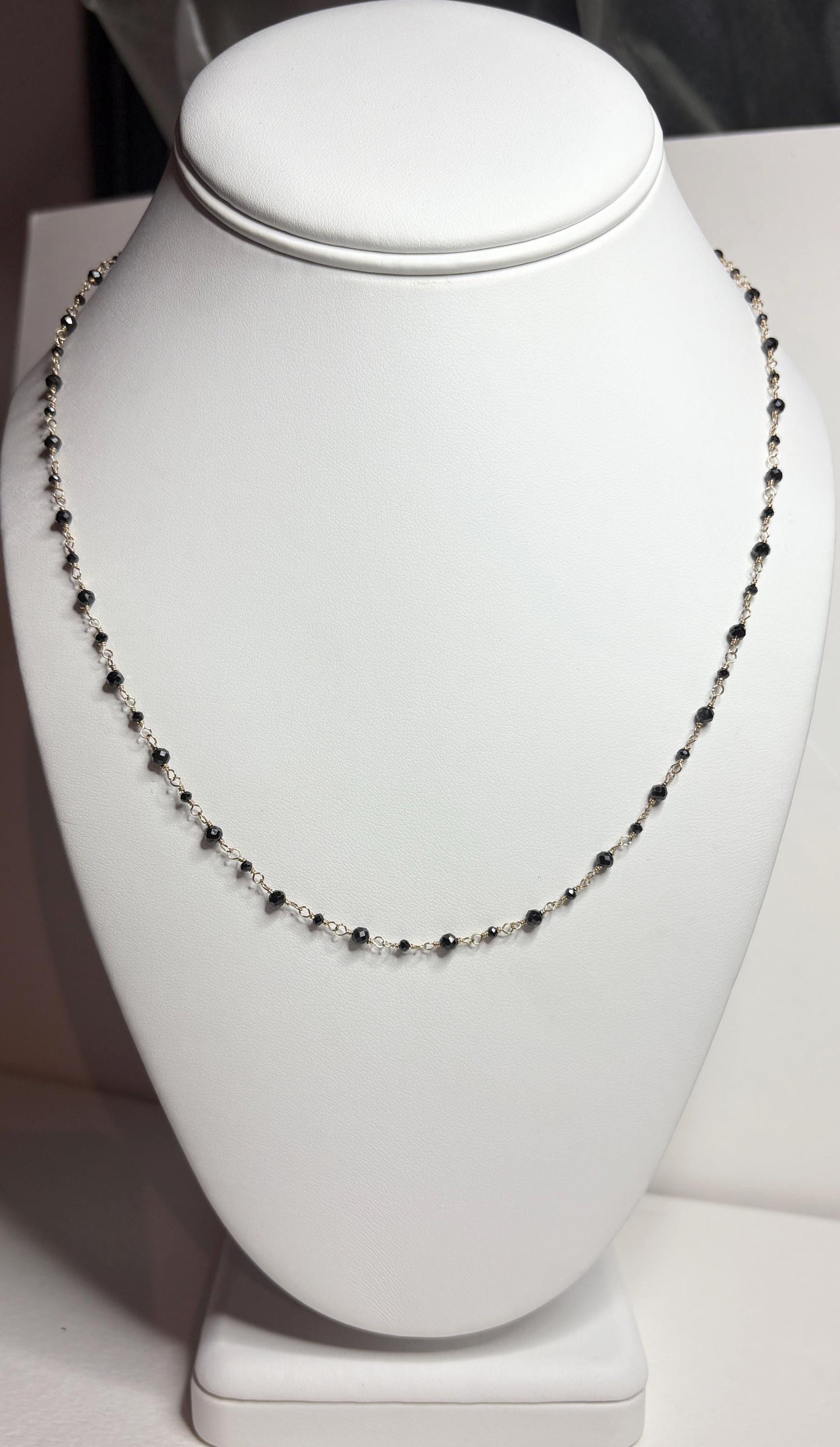 A delicate 14k gold necklace with small black diamond beads.