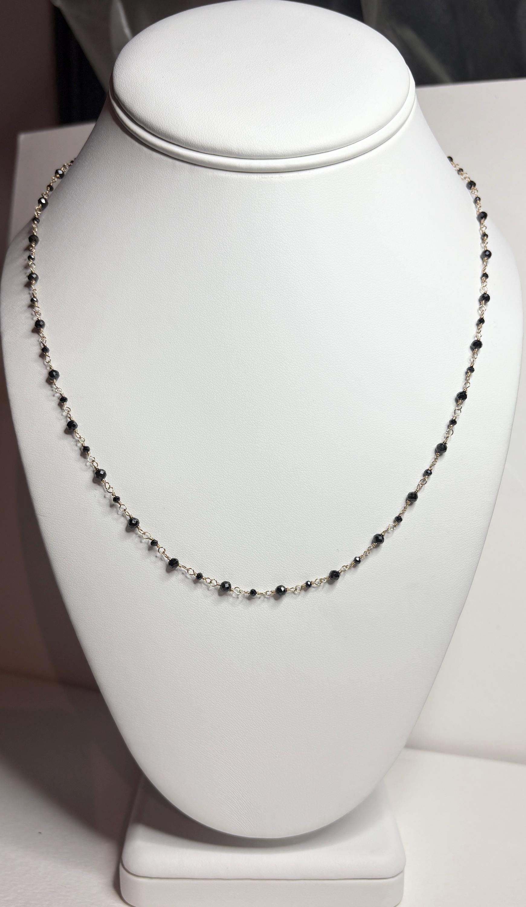 A delicate 14k gold necklace with small black diamond beads.