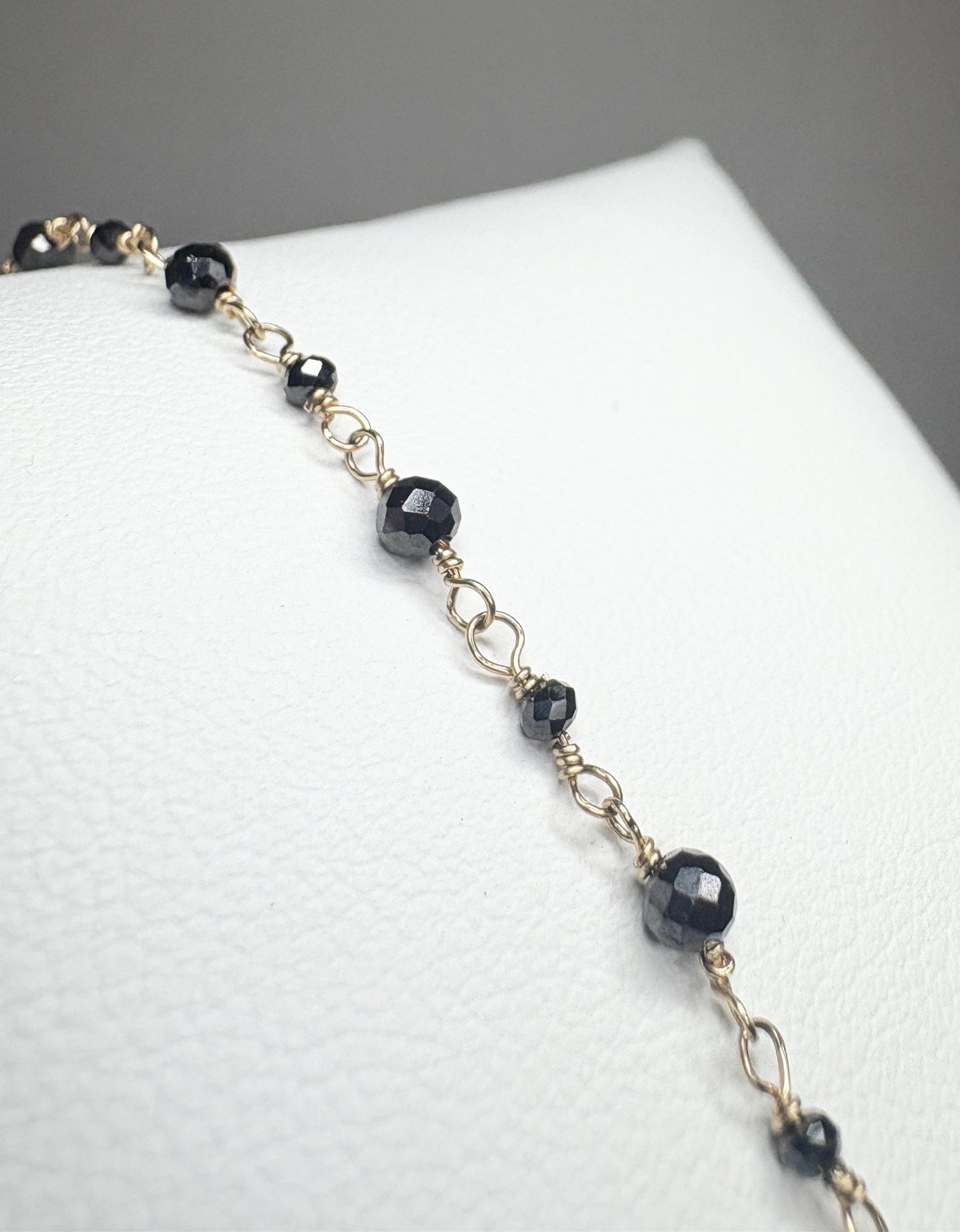 A 14k gold bracelet with faceted black diamond beads.