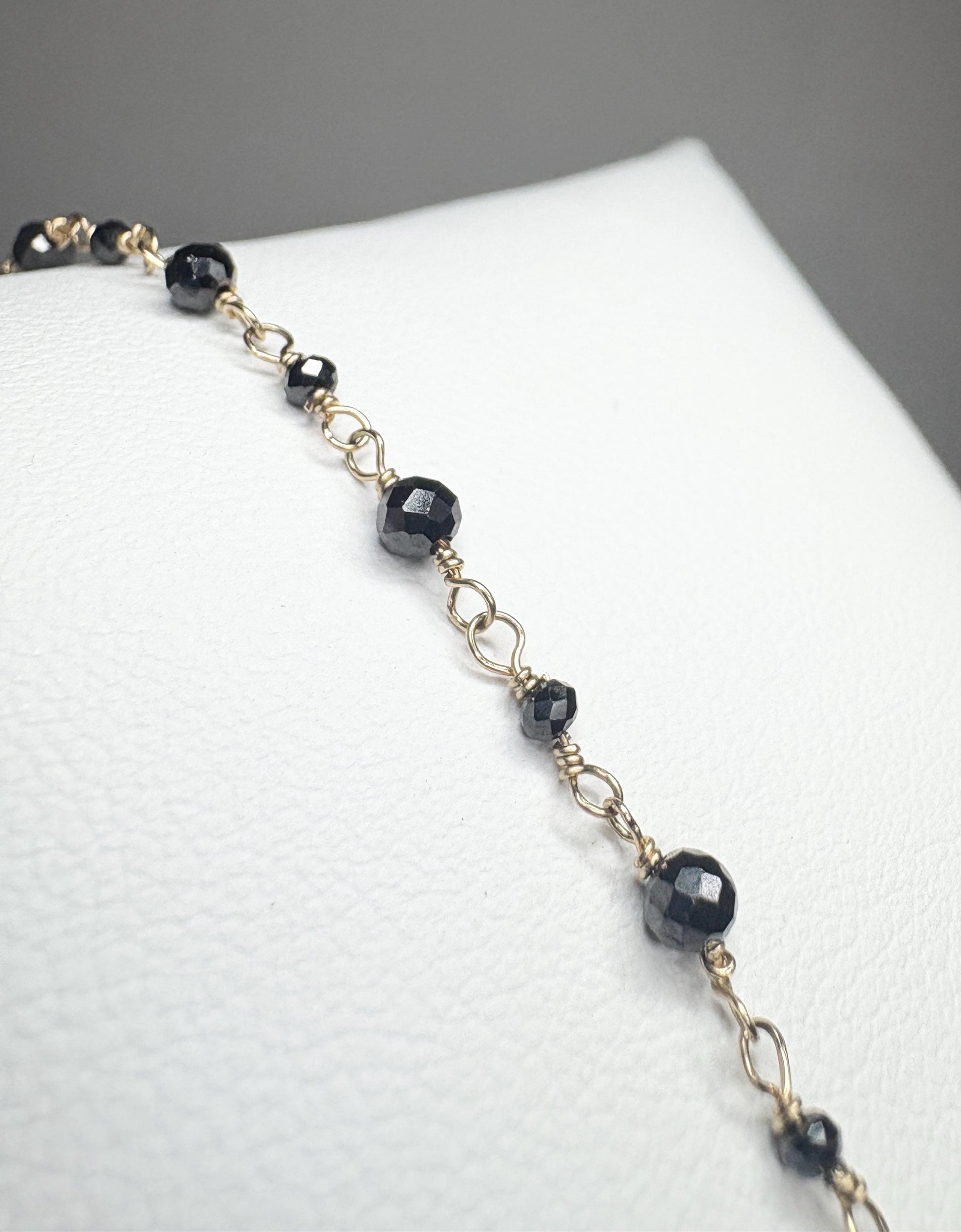 A 14k gold bracelet with faceted black diamond beads.