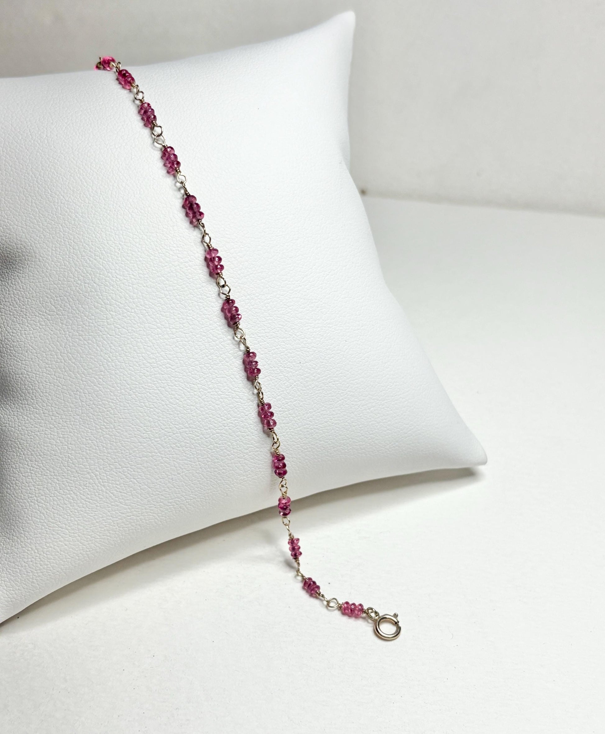 A delicate bracelet with small, faceted hot pink spinel beads and a gold clasp.