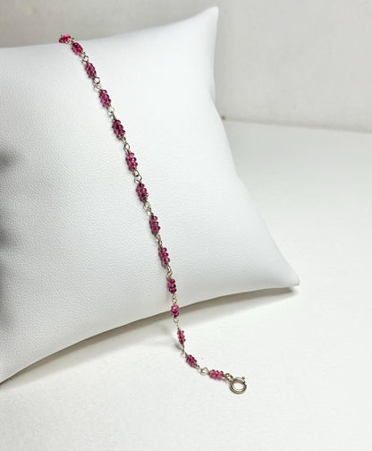 A delicate bracelet with small, faceted hot pink spinel beads and a gold clasp.
