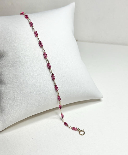 A delicate bracelet with small, faceted hot pink spinel beads and a gold clasp.