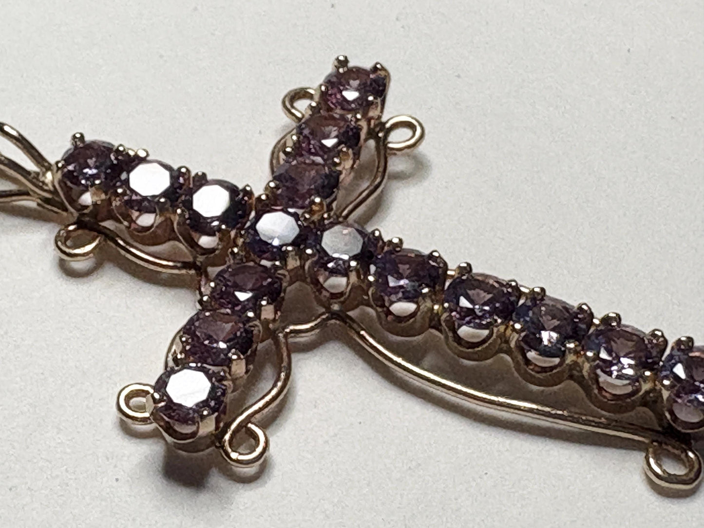 A large 14k gold cross pendant necklace with purple lab-grown sapphires.