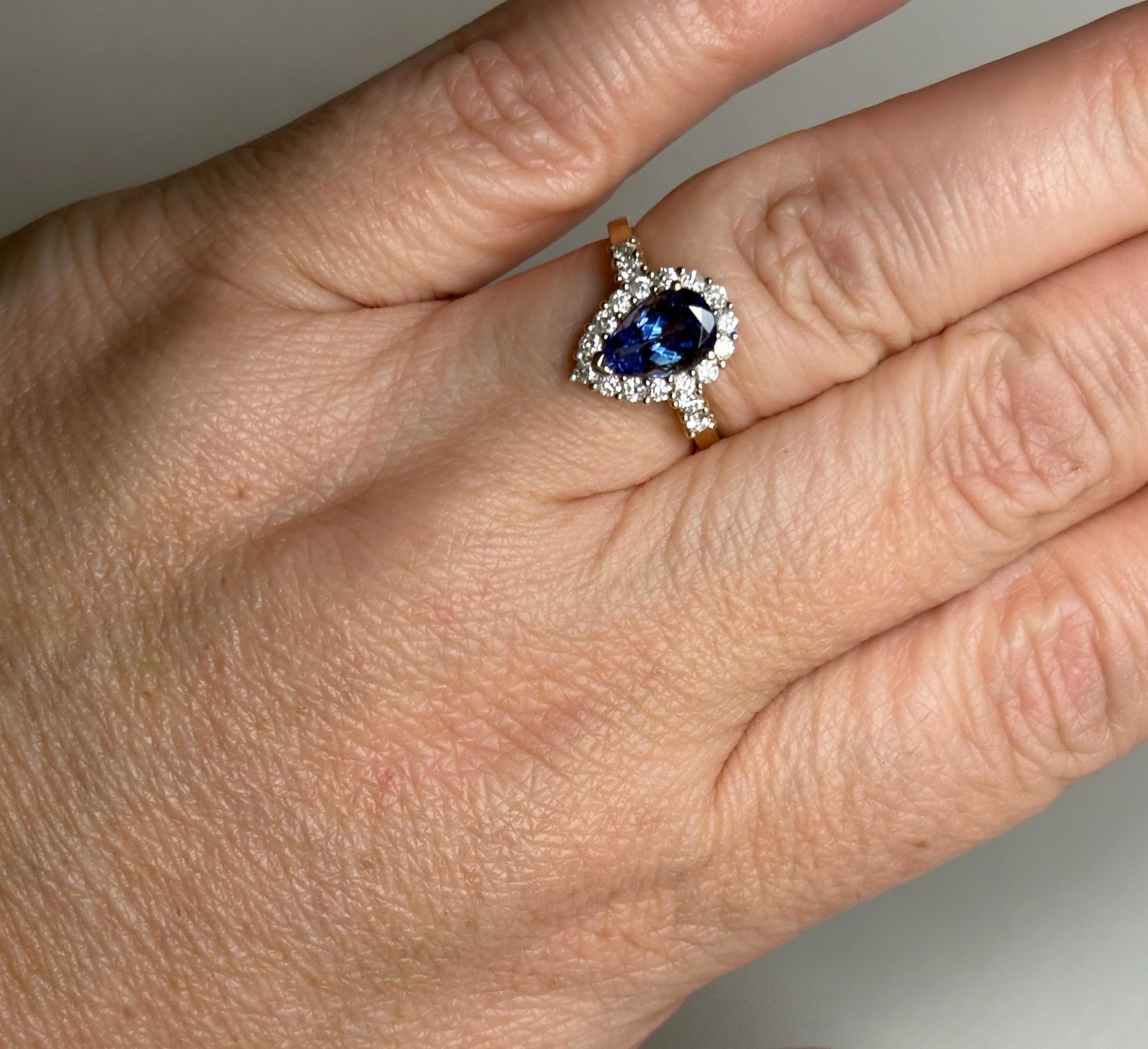 Pear tanzanite and diamond halo ring in 14k gold.