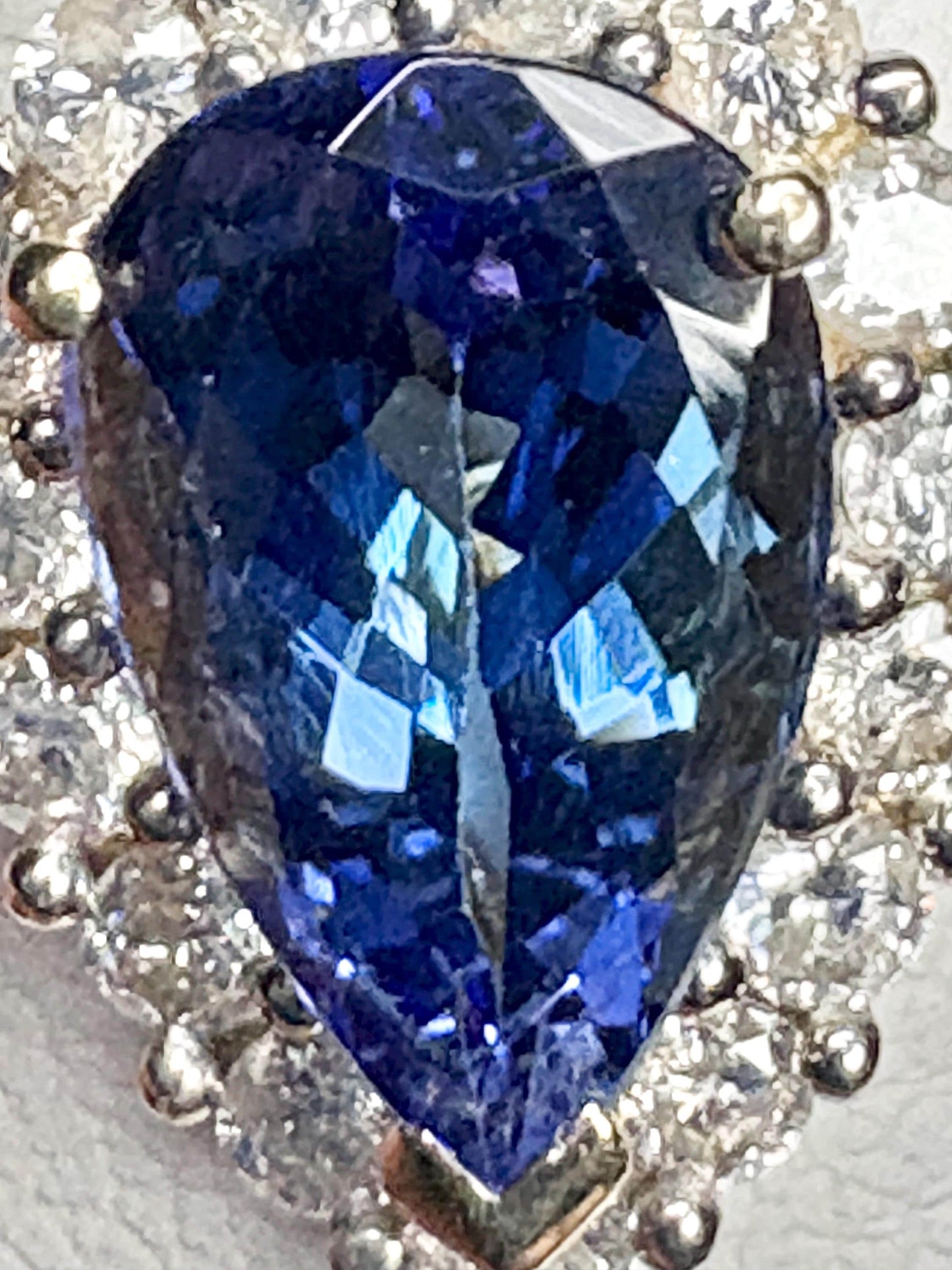 Pear-shaped tanzanite ring with diamond halo in 14k gold.