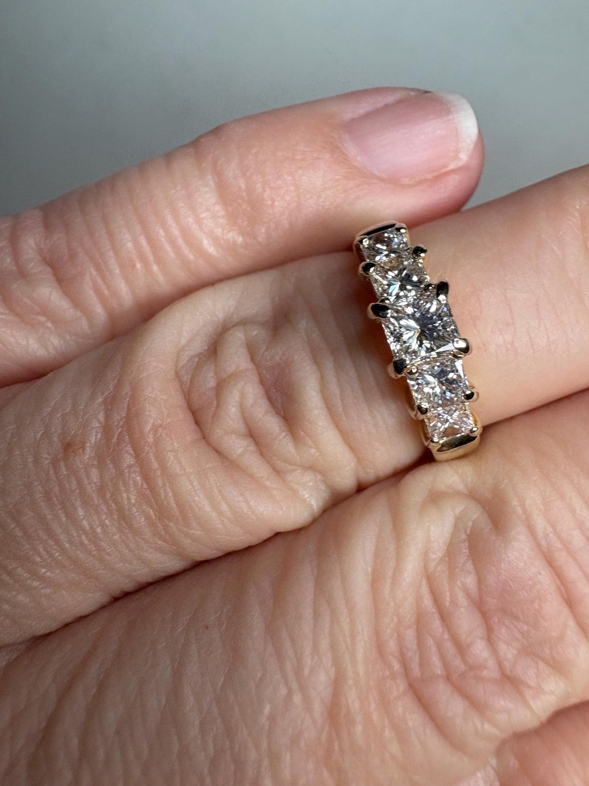 A 14k yellow gold anniversary band with five princess-cut diamonds.