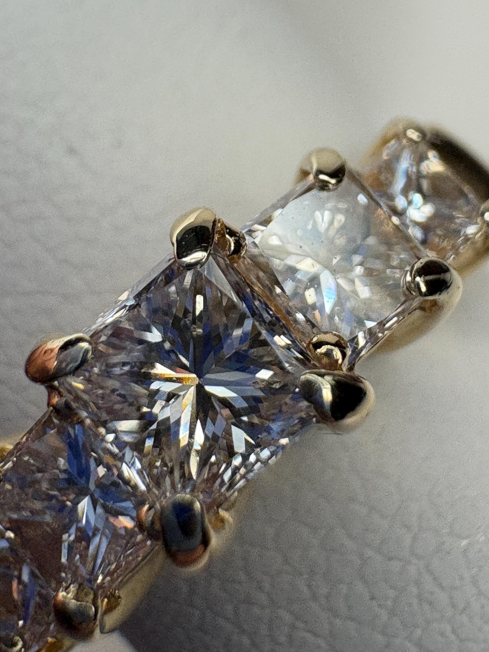 A 14k yellow gold band ring with five princess-cut diamonds.