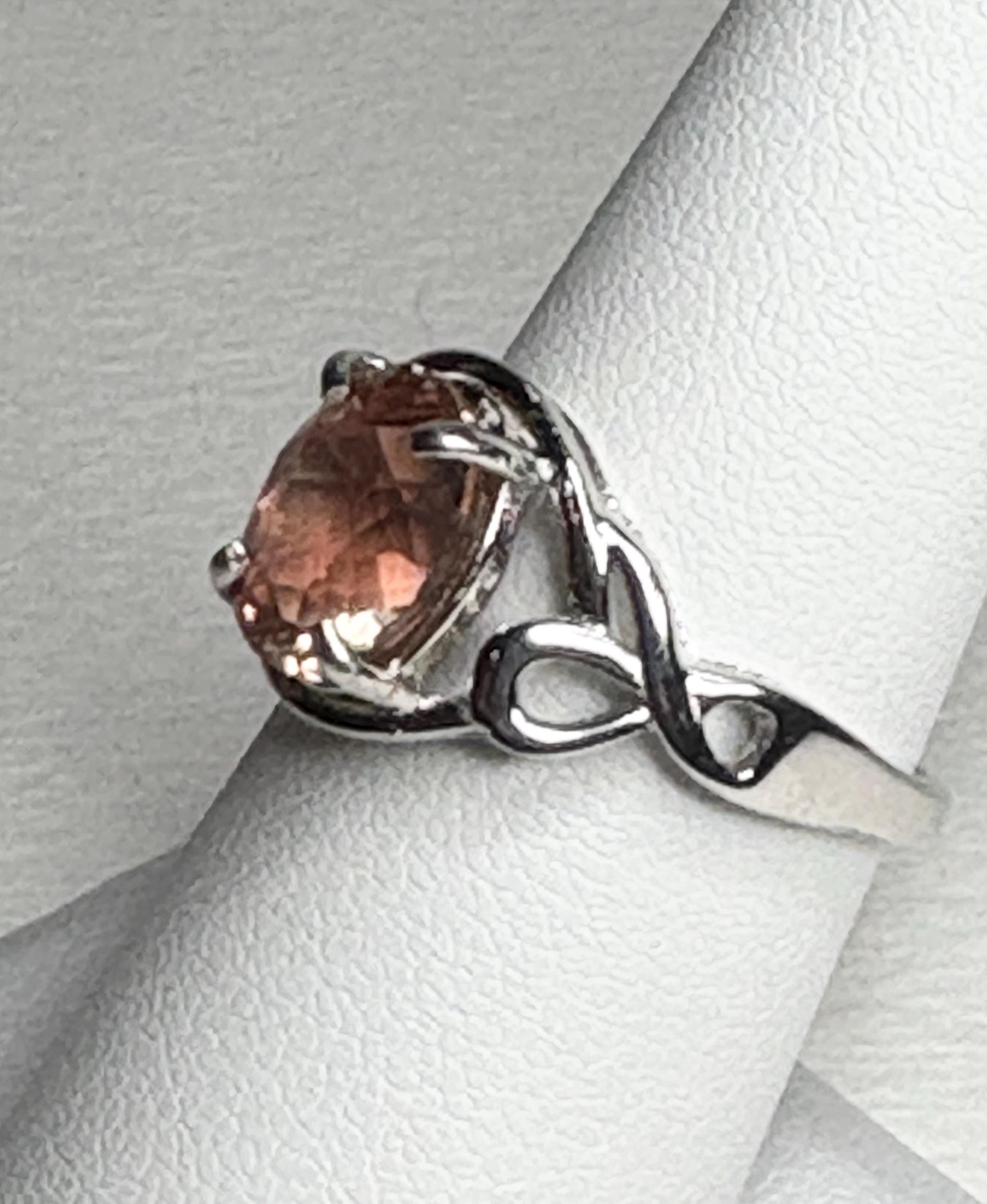 Sterling silver ring with an oval Oregon sunstone in a free-form ribbon setting.