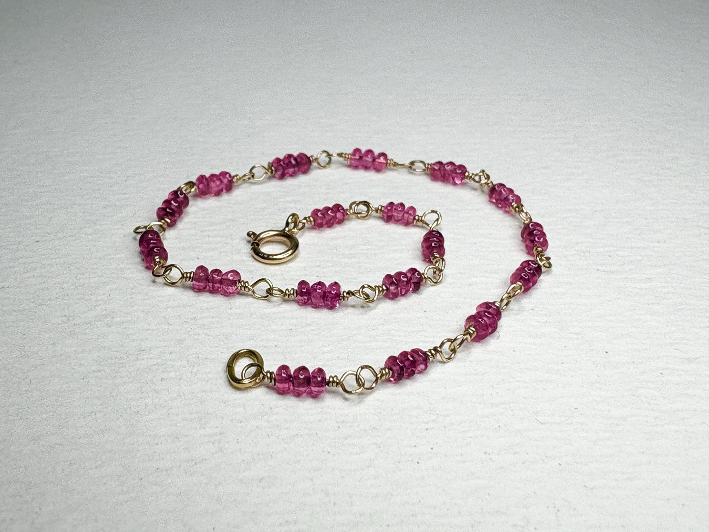 A delicate 14k gold bracelet with small, faceted hot pink spinel beads.