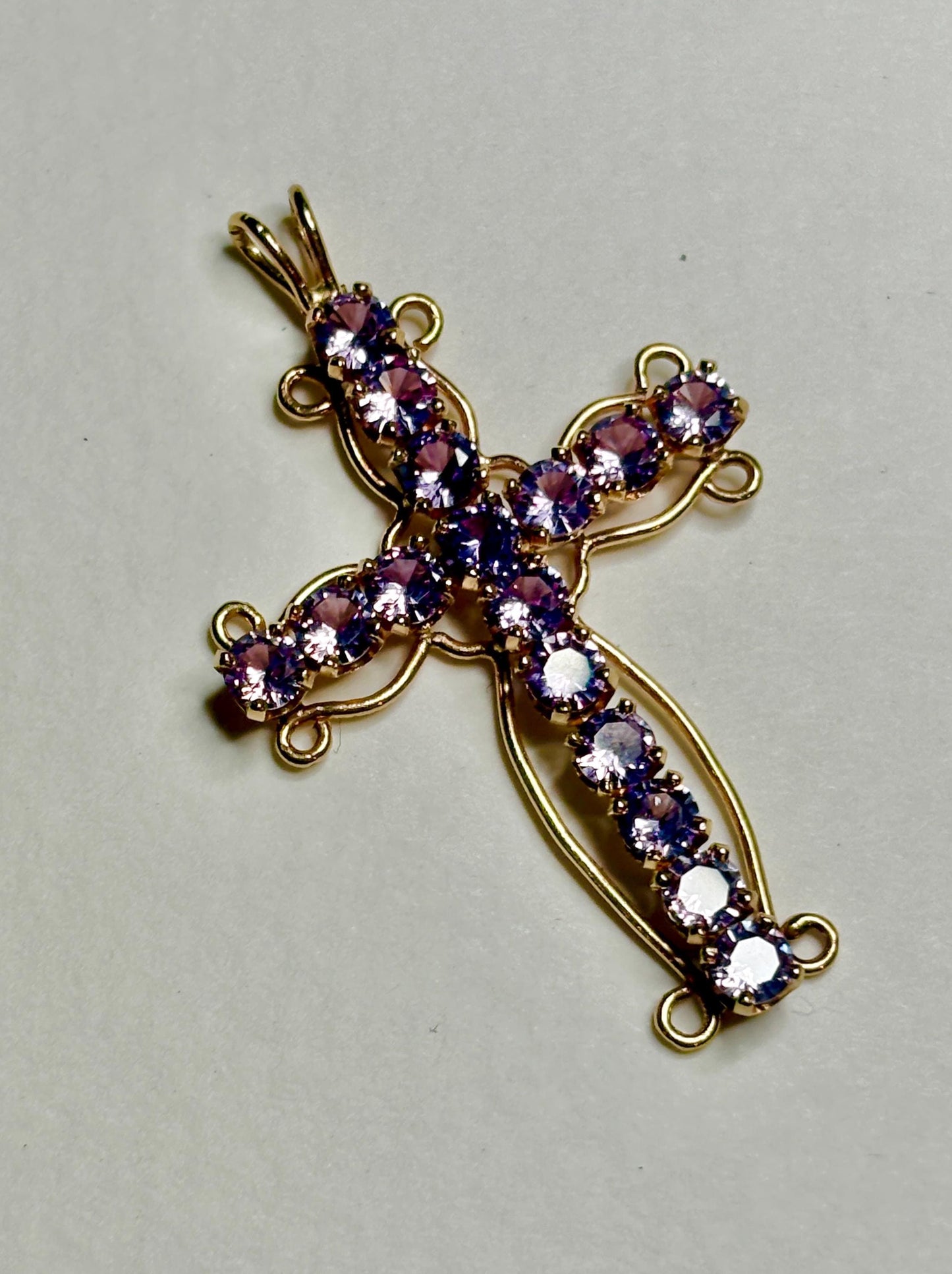 A 14k gold cross pendant with purple gemstones.