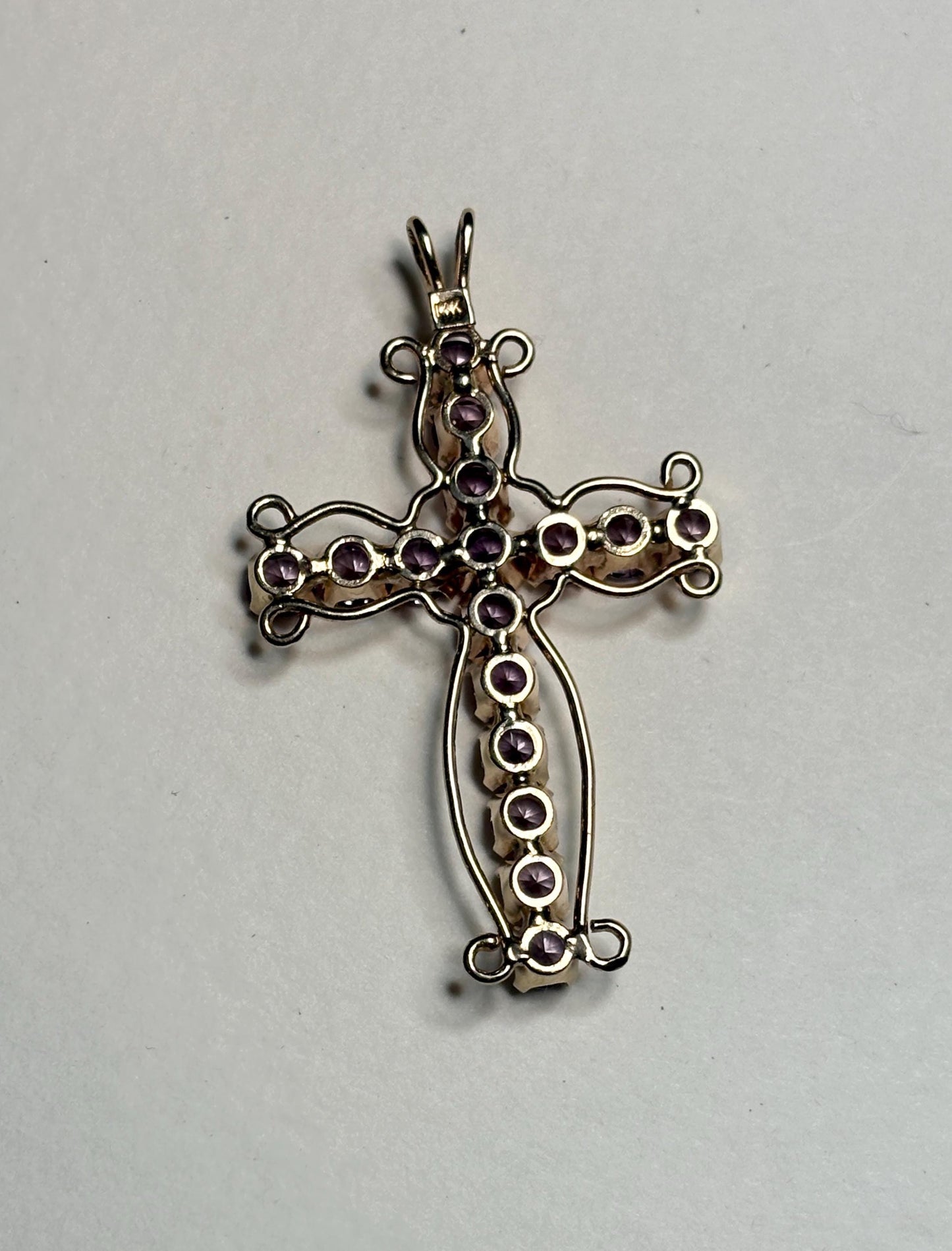 A 14k gold cross pendant with purple lab-created sapphires.