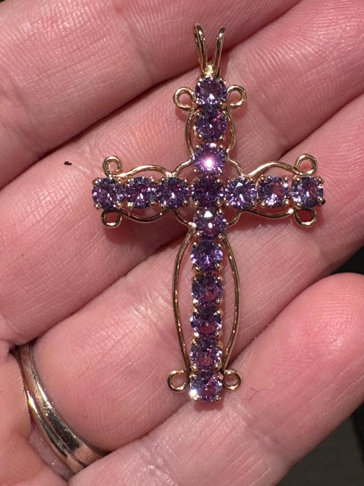 A 14k gold cross pendant with purple lab-grown sapphires.
