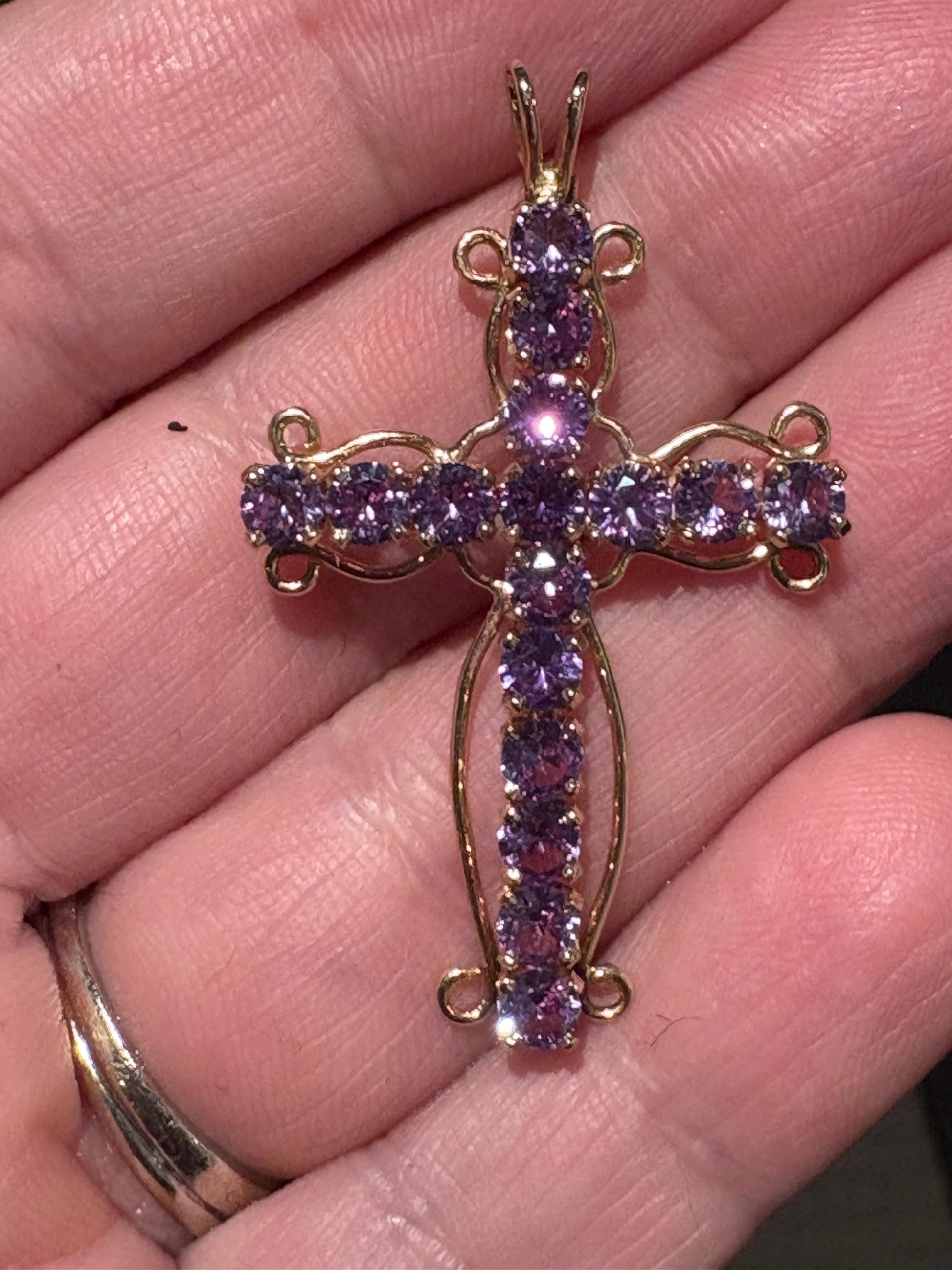 A 14k gold cross pendant with purple lab-grown sapphires.