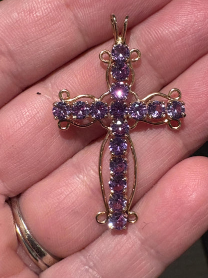 A 14k gold cross pendant with purple lab-grown sapphires.