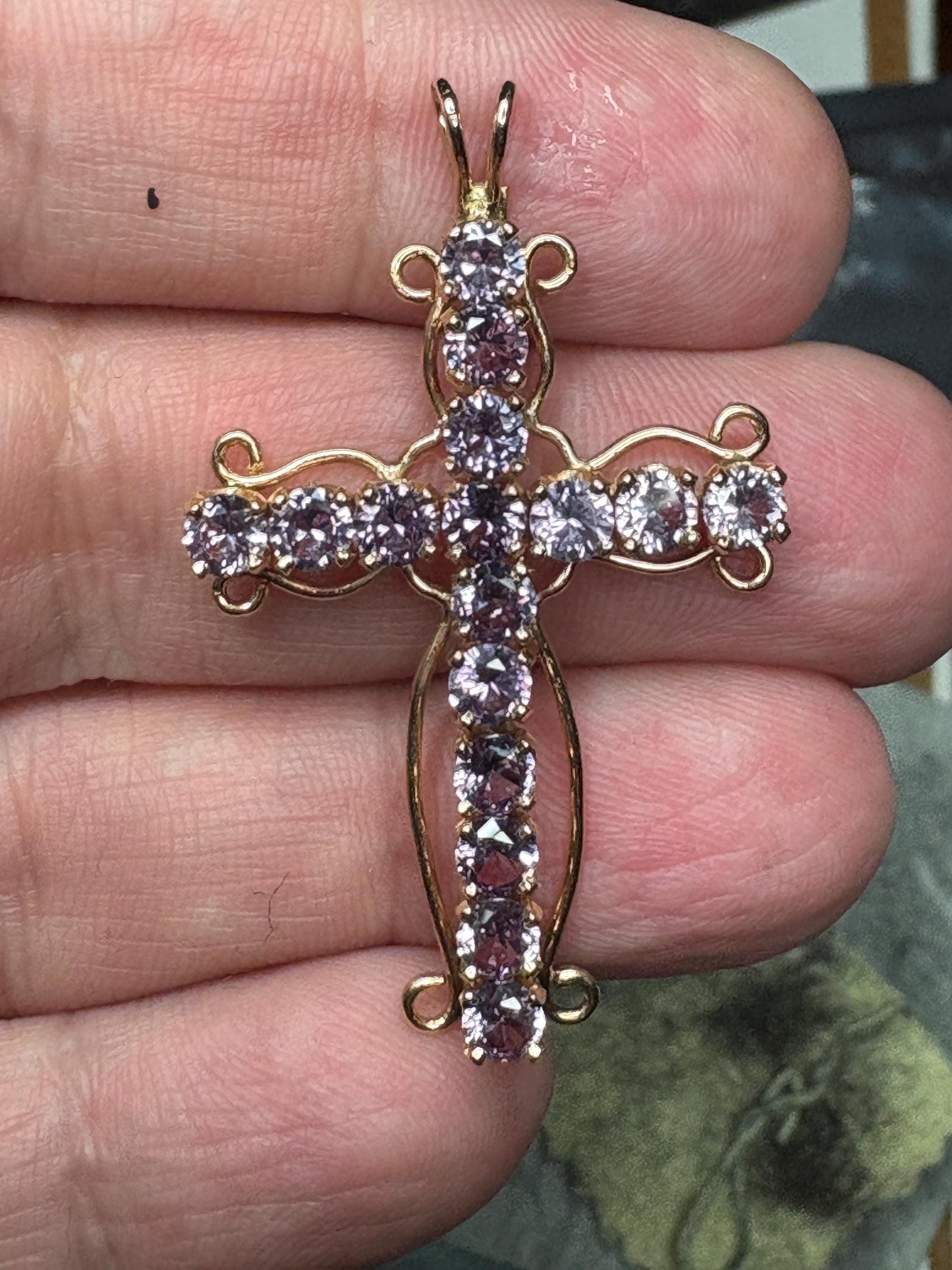 A 14k gold cross pendant with purple lab-grown sapphires.