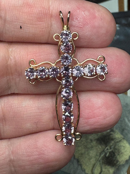 A 14k gold cross pendant with purple lab-grown sapphires.