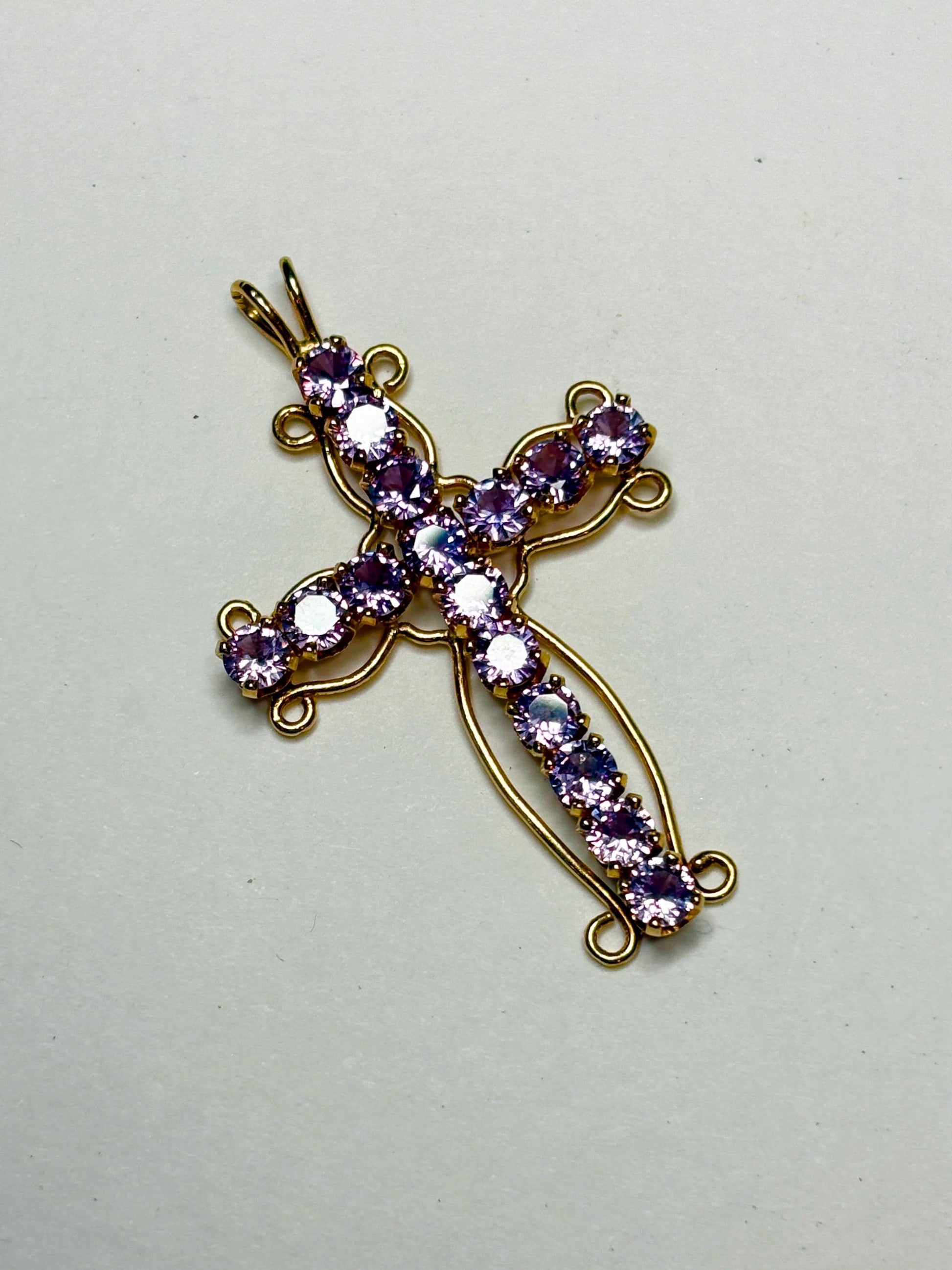 A 14k gold cross pendant necklace with purple lab-grown sapphires.