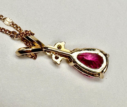 A gold pendant necklace with a pear-shaped rubellite tourmaline and diamond accents.