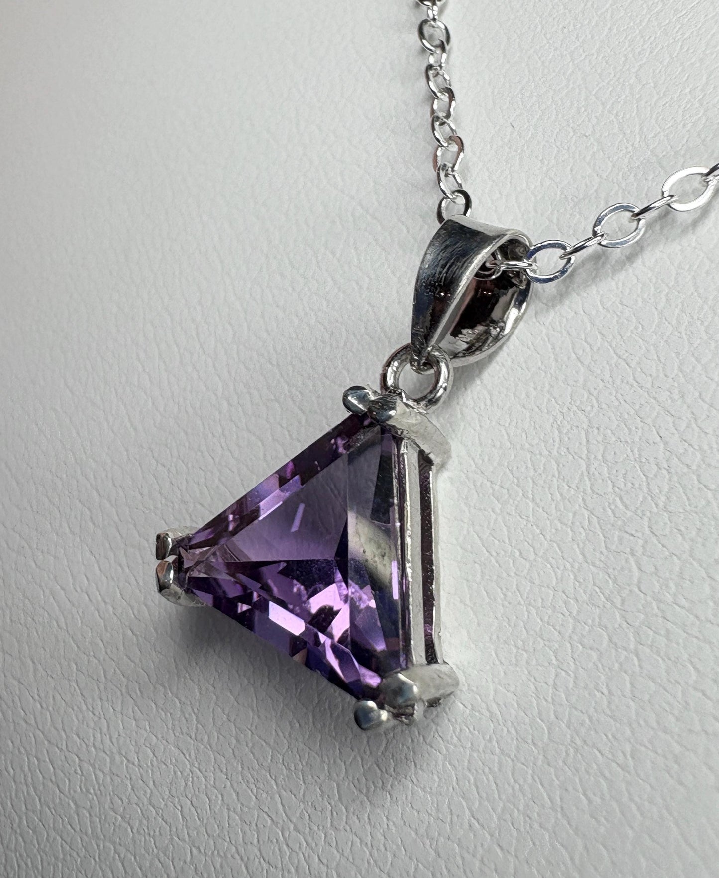 Sterling silver pendant necklace with a triangular amethyst gemstone.
