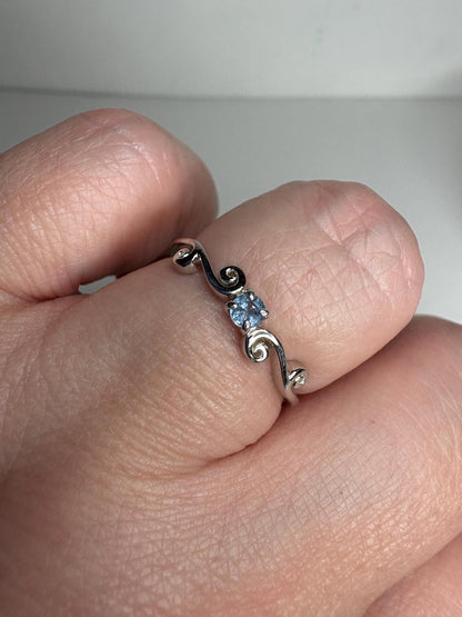 Sterling silver ring with a light blue sapphire and swirl band.