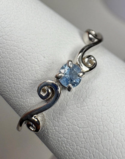 Sterling silver ring with a light blue sapphire and swirl band.