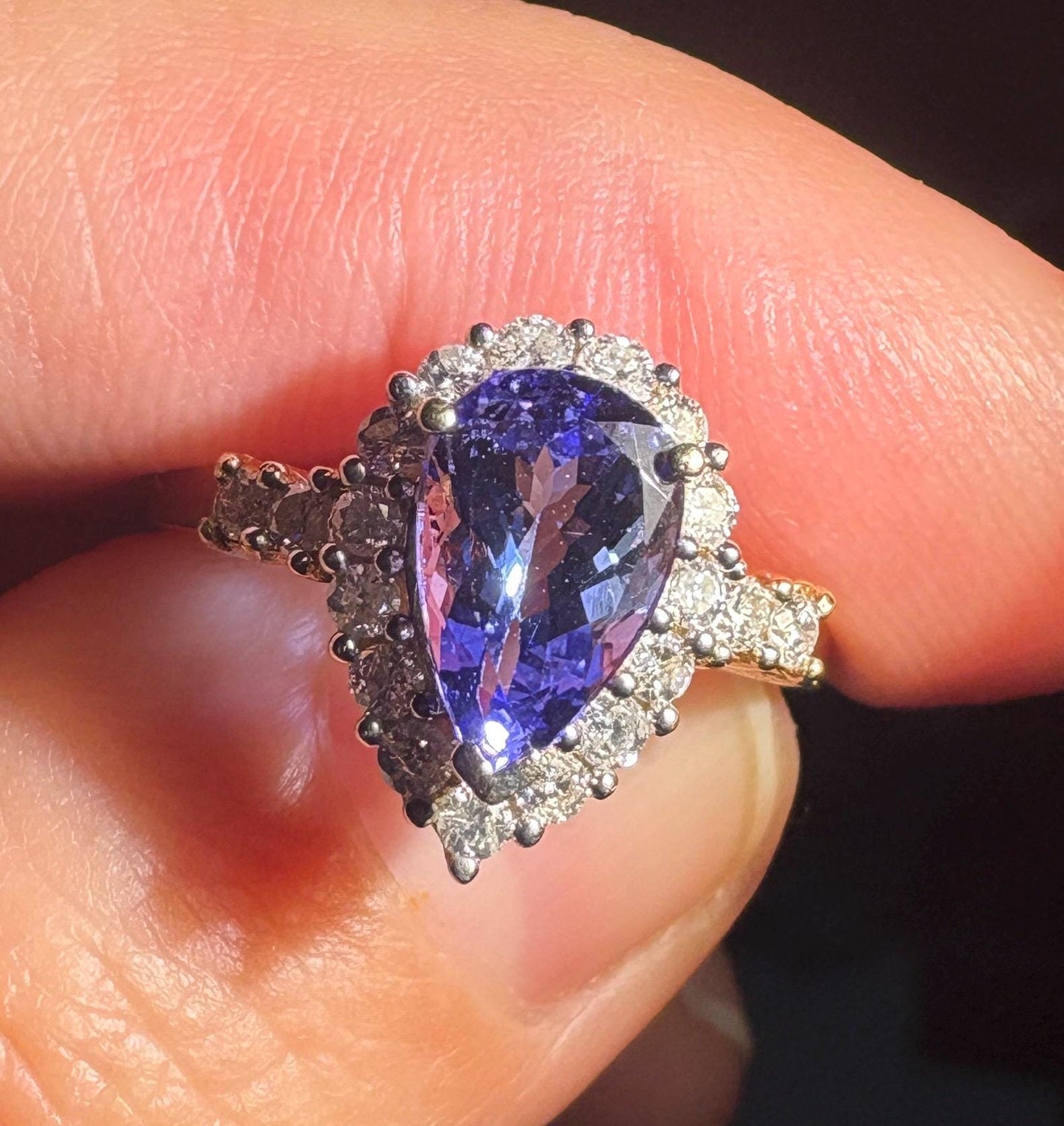 Pear-shaped tanzanite ring with diamond halo in 14k gold.