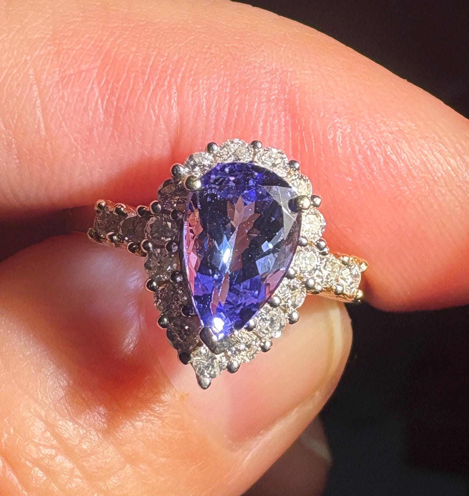 Pear-shaped tanzanite ring with diamond halo in 14k gold.