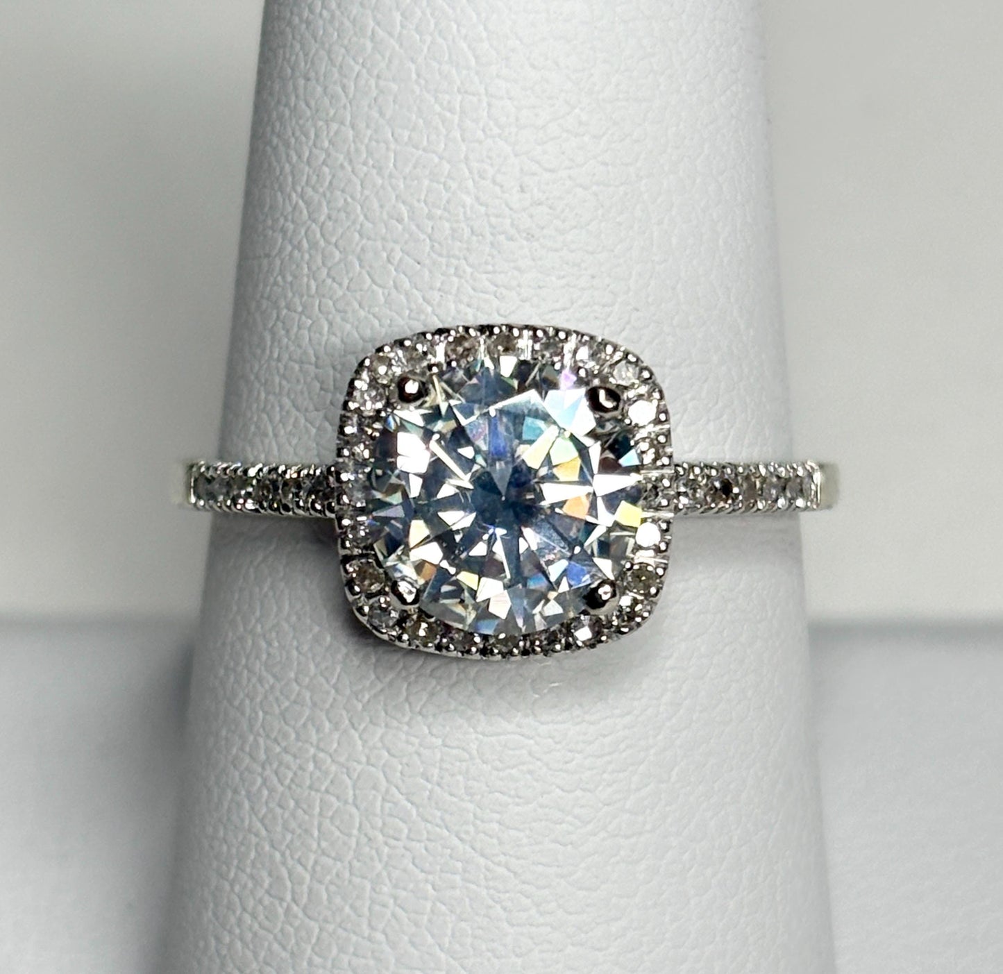 A white gold ring with a large moissanite center stone surrounded by small diamonds.