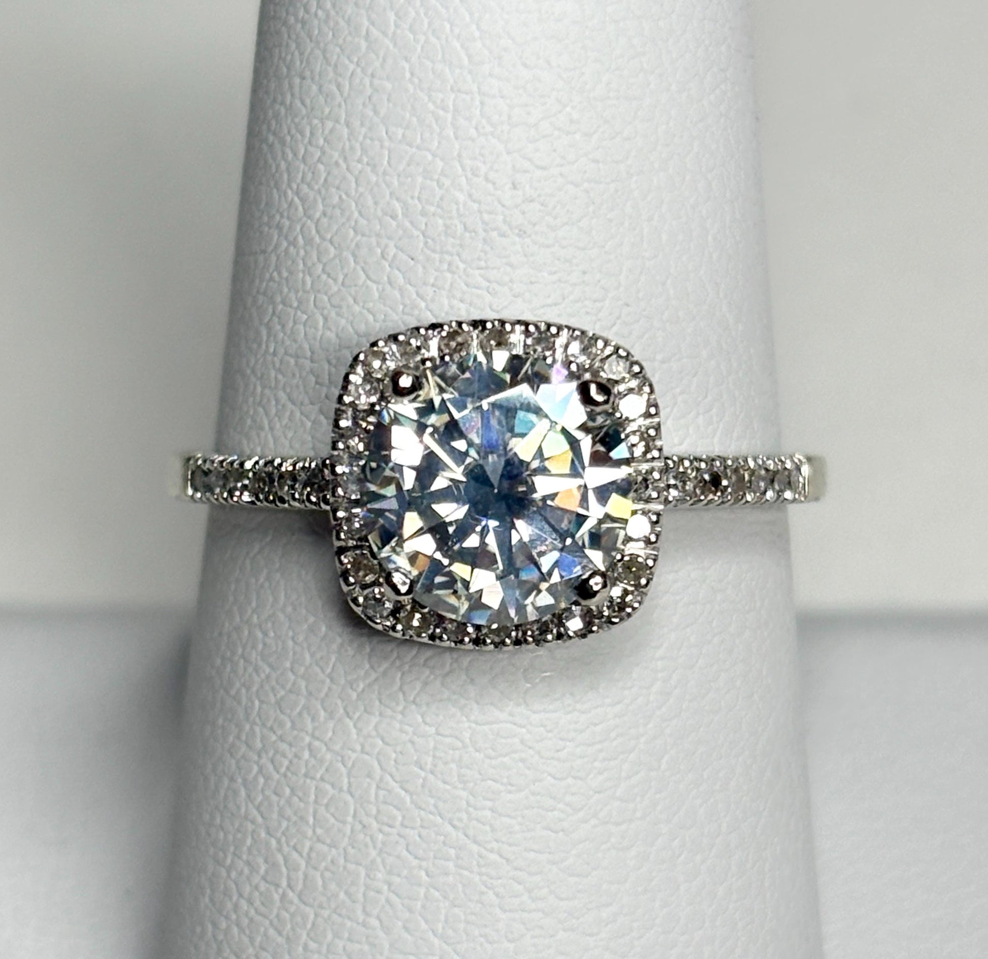 A white gold ring with a large moissanite center stone surrounded by small diamonds.