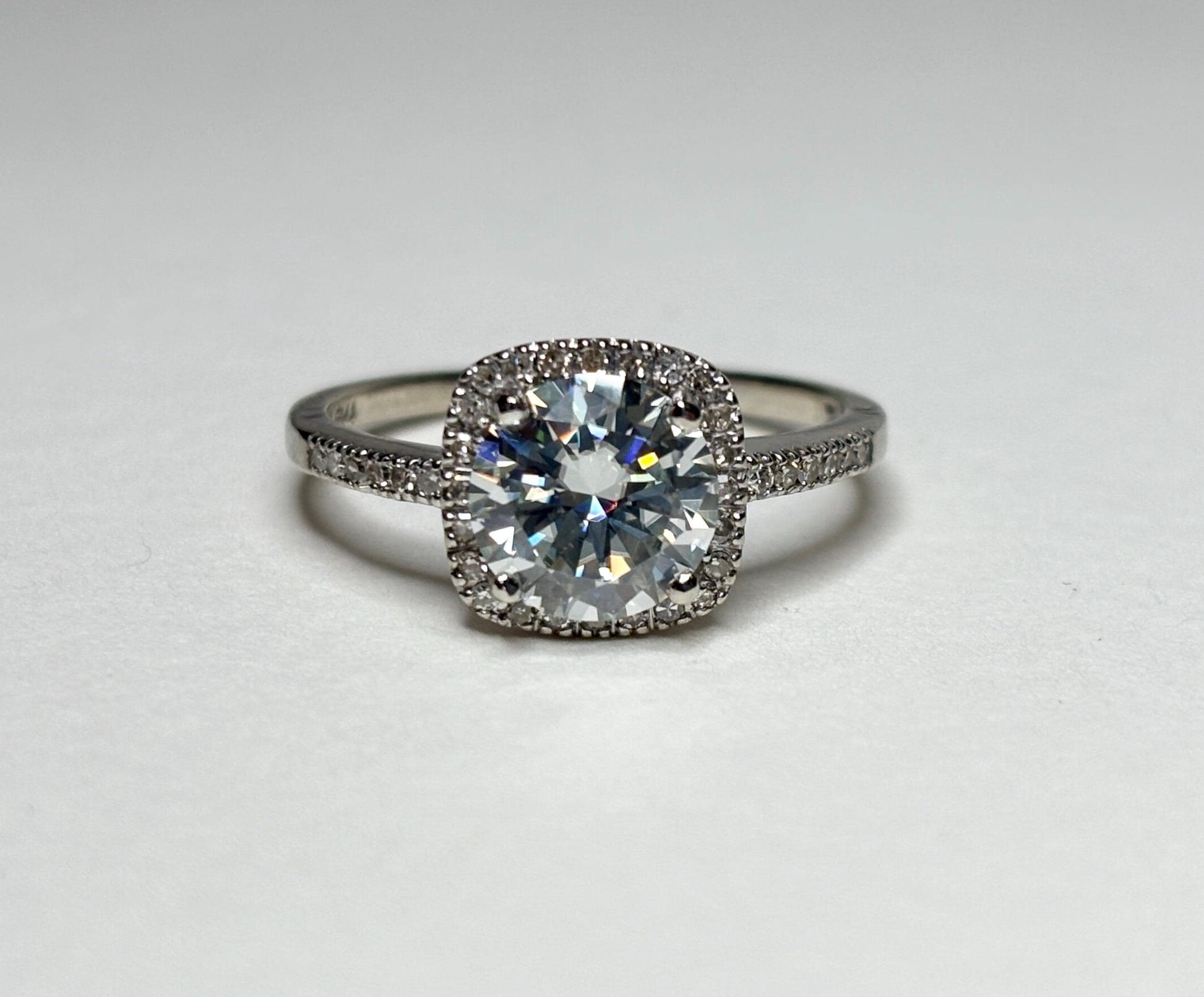 A 10k white gold ring with a large moissanite center stone surrounded by small diamonds.