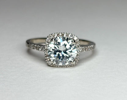 A white gold ring with a large moissanite center stone surrounded by small diamonds.