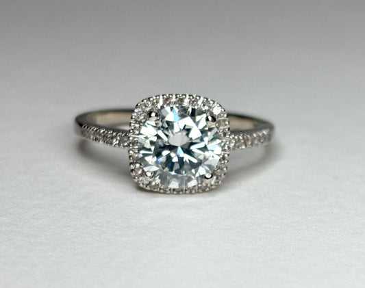A white gold ring with a large moissanite center stone surrounded by small diamonds.